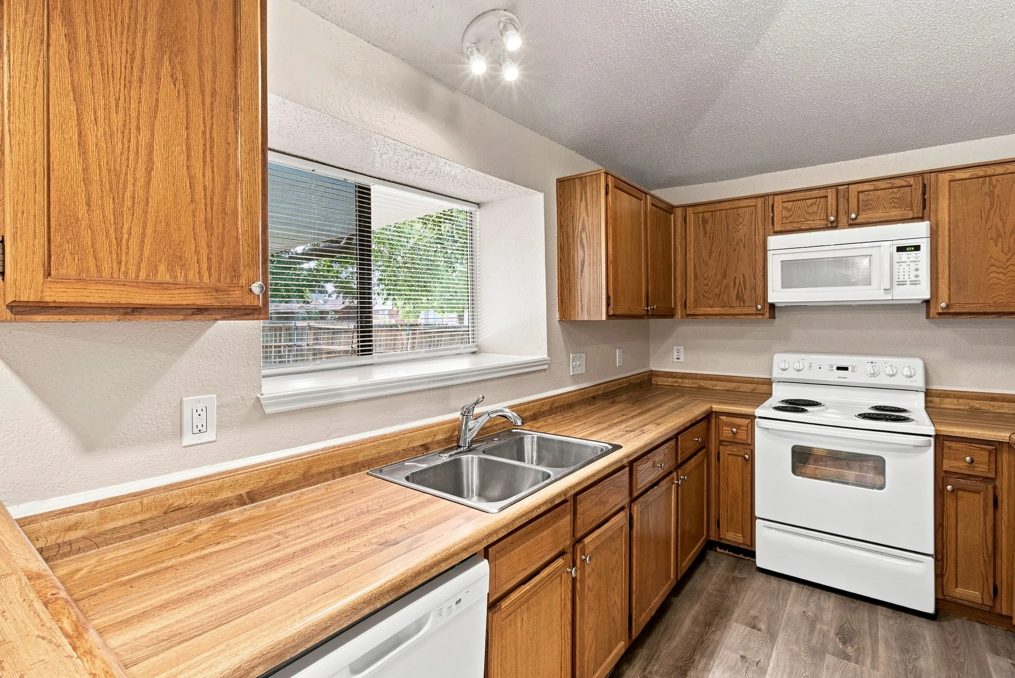 Kitchen featuring wood-finish cabinetry, butcher block style countertops, and a double basin stainless steel sink