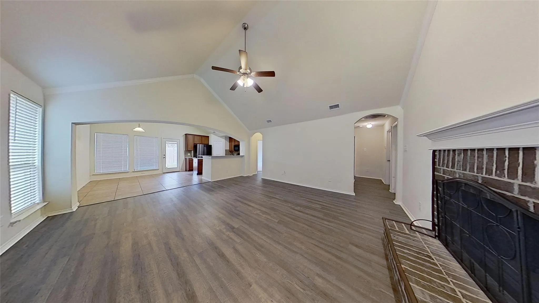 Spacious living area featuring vaulted ceilings, wood-finish flooring, and an arched entryway