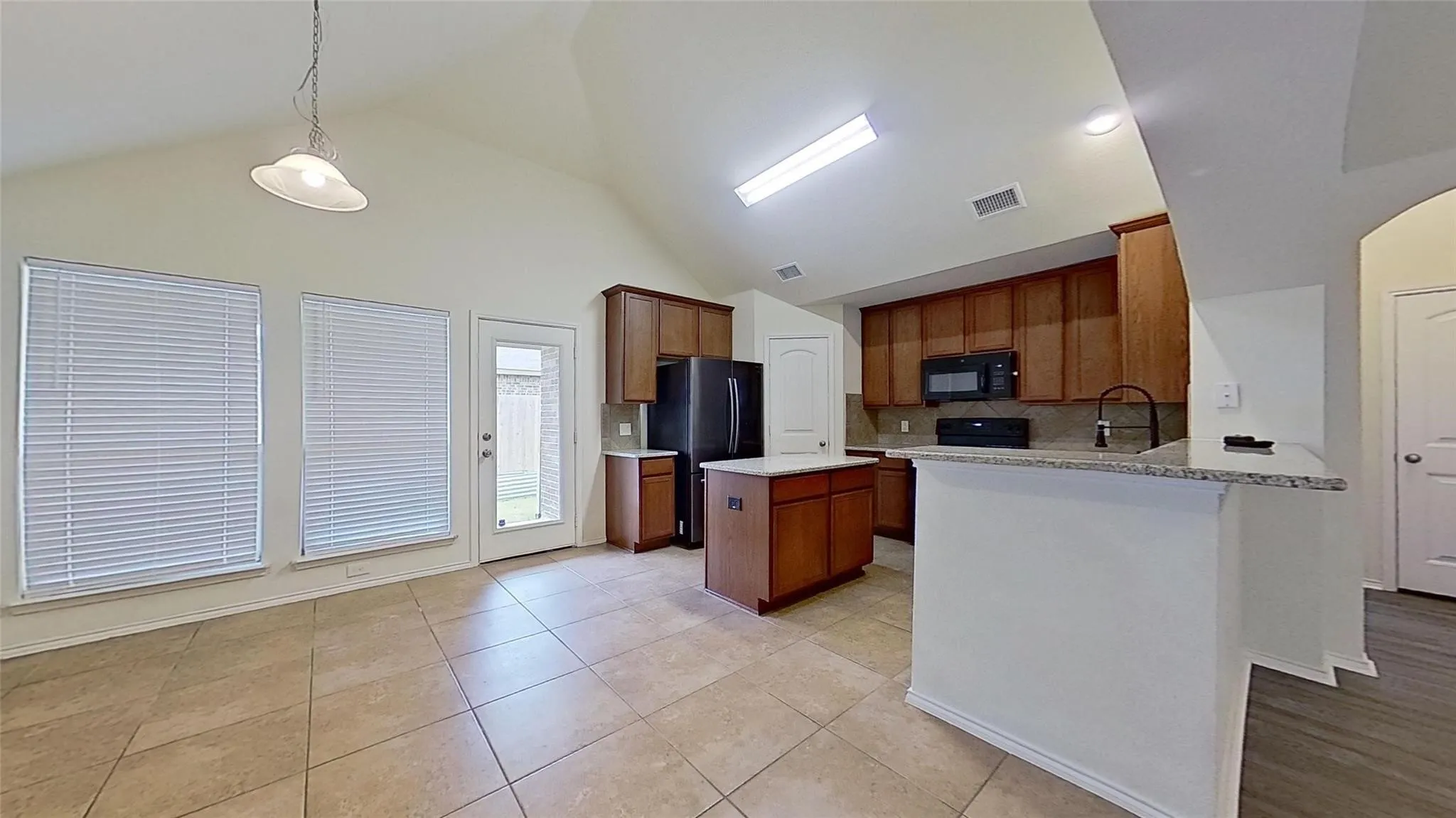 Kitchen featuring a central island, wood cabinetry, stone countertops, and tile flooring