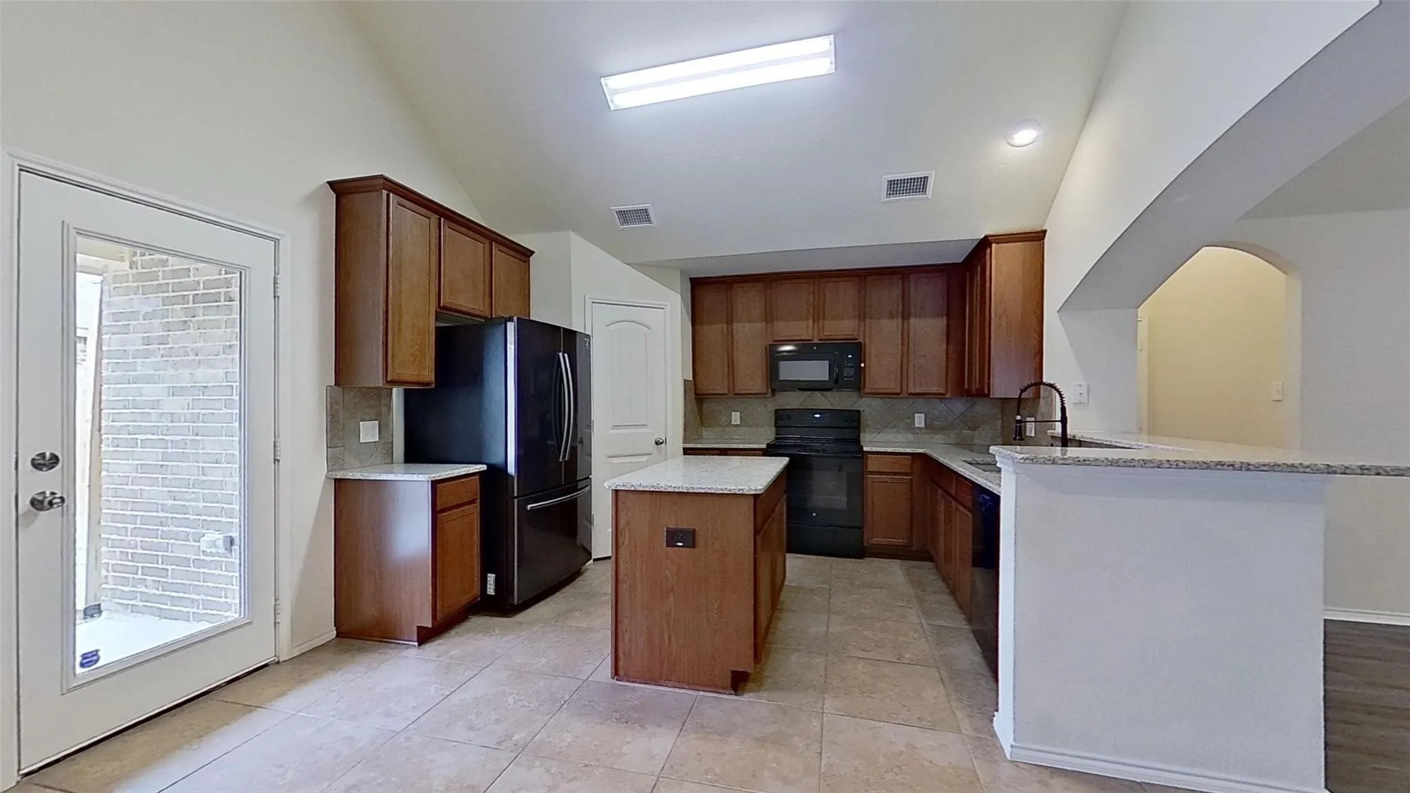 Spacious kitchen featuring an island, granite countertops, tile flooring, recessed lighting, and a glass-paneled back door
