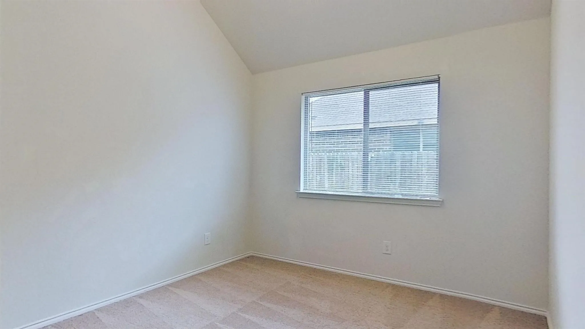 Room with vaulted ceiling, neutral wall paint, and beige patterned carpet flooring