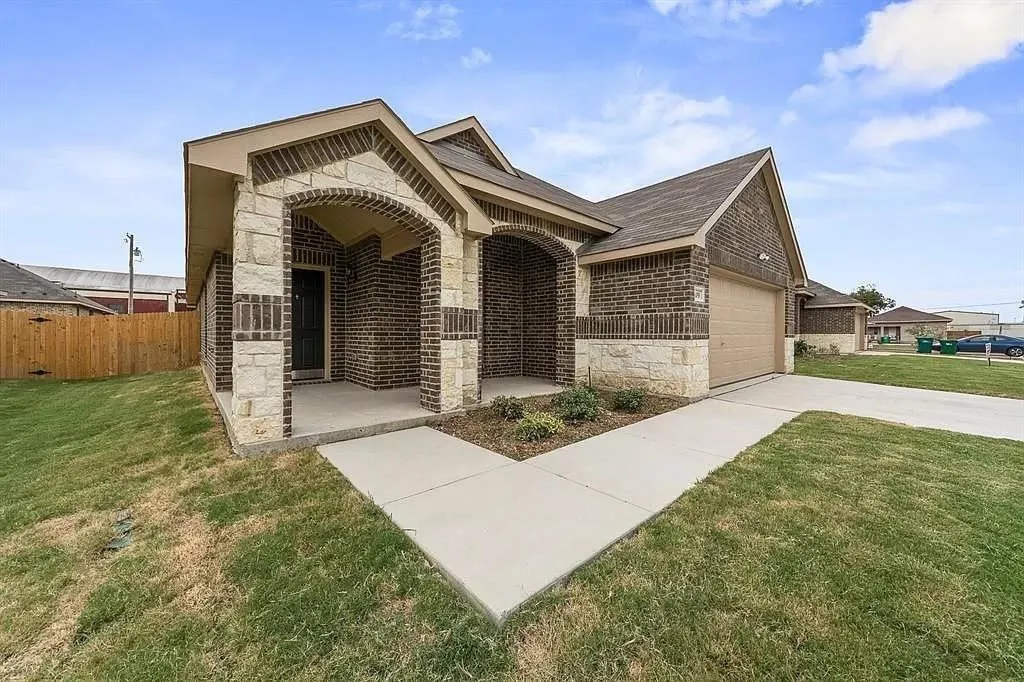 Brick and stone veneer exterior featuring an arched entryway, covered porch, and an attached garage with an automatic door