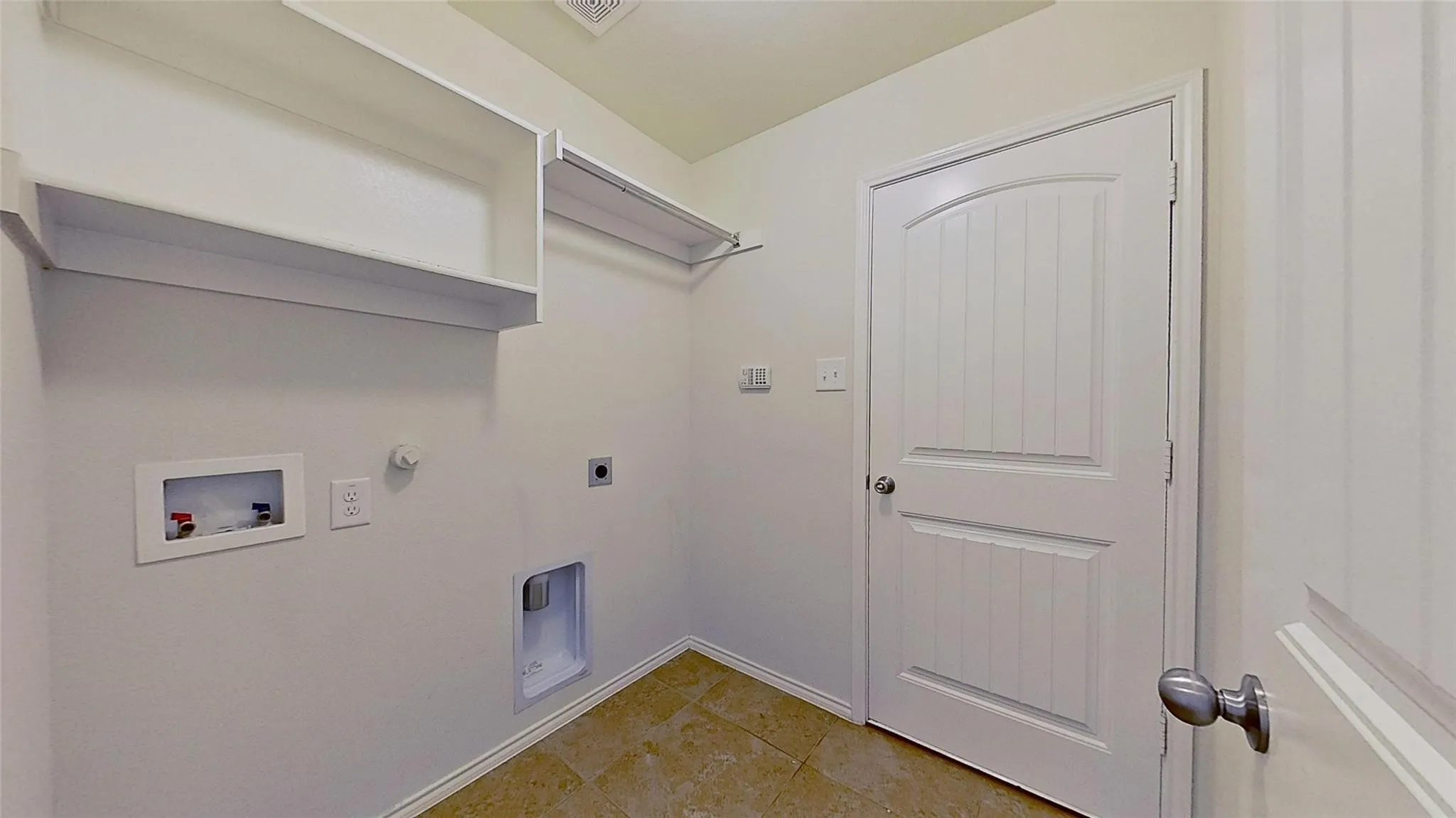 Dedicated utility space featuring tile flooring and white walls