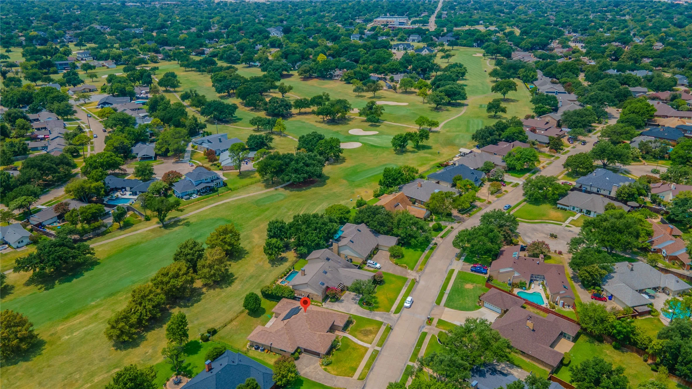 Aerial perspective showcasing a residential area with a golf course backdrop