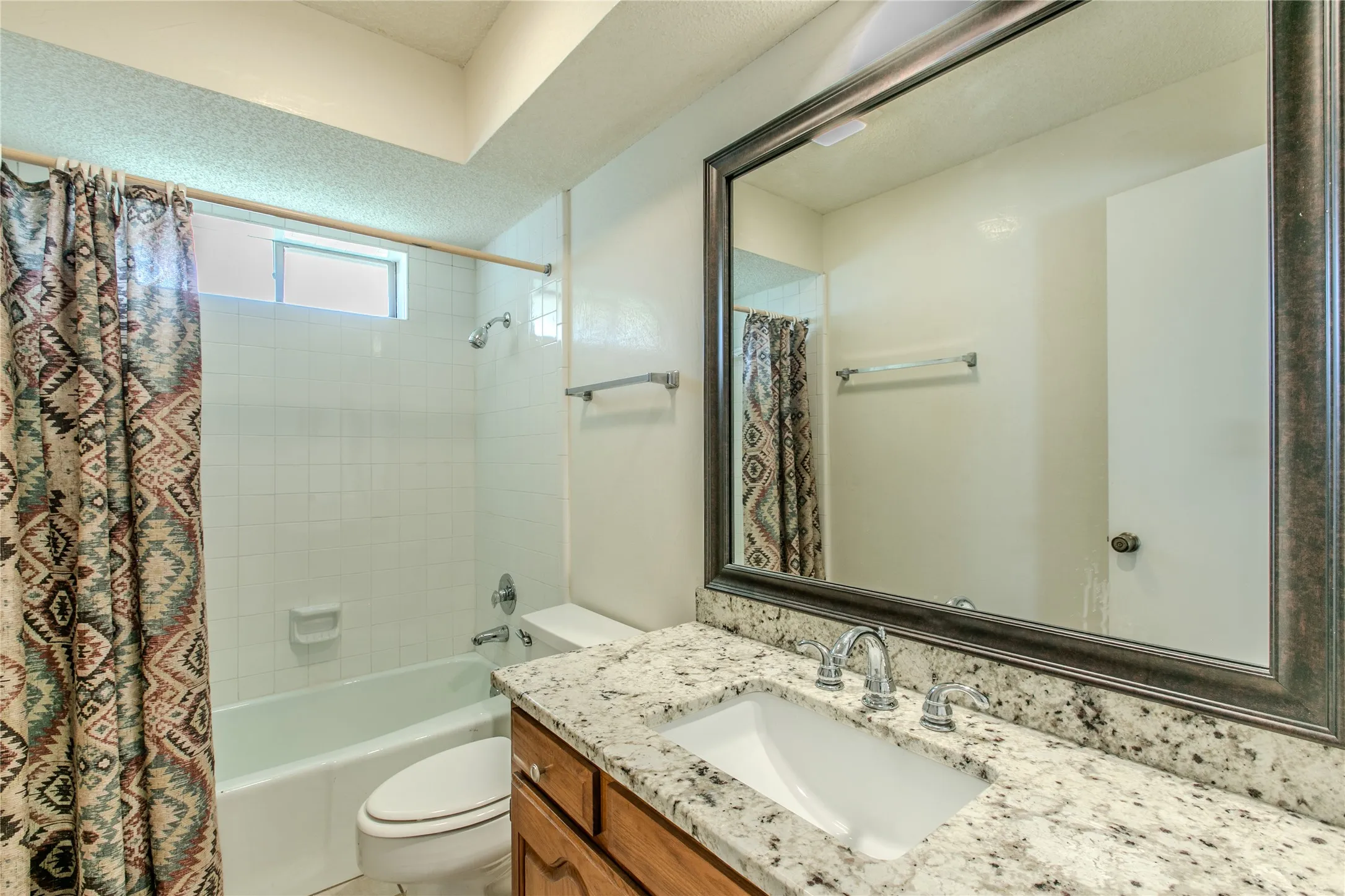 Bathroom vanity featuring a light-colored speckled countertop, undermount sink, and chrome faucet