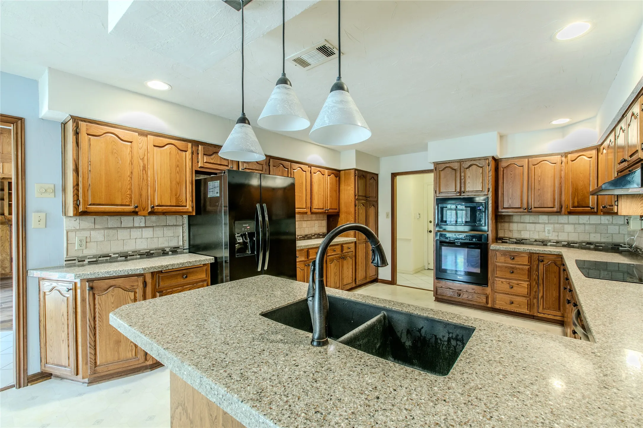Kitchen featuring an island with a dual basin sink and gooseneck faucet