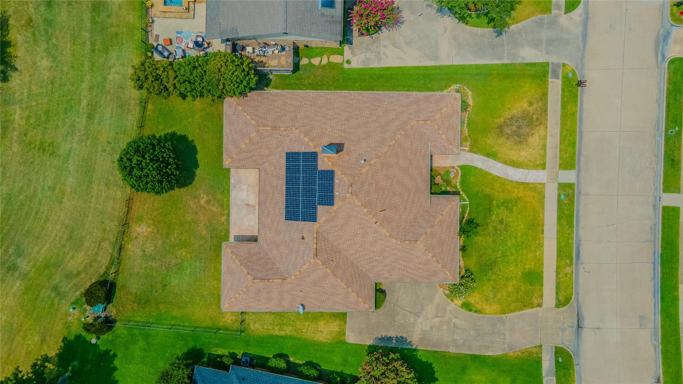 Aerial property overview showcasing a tiled roof, integrated solar panels, and a concrete driveway