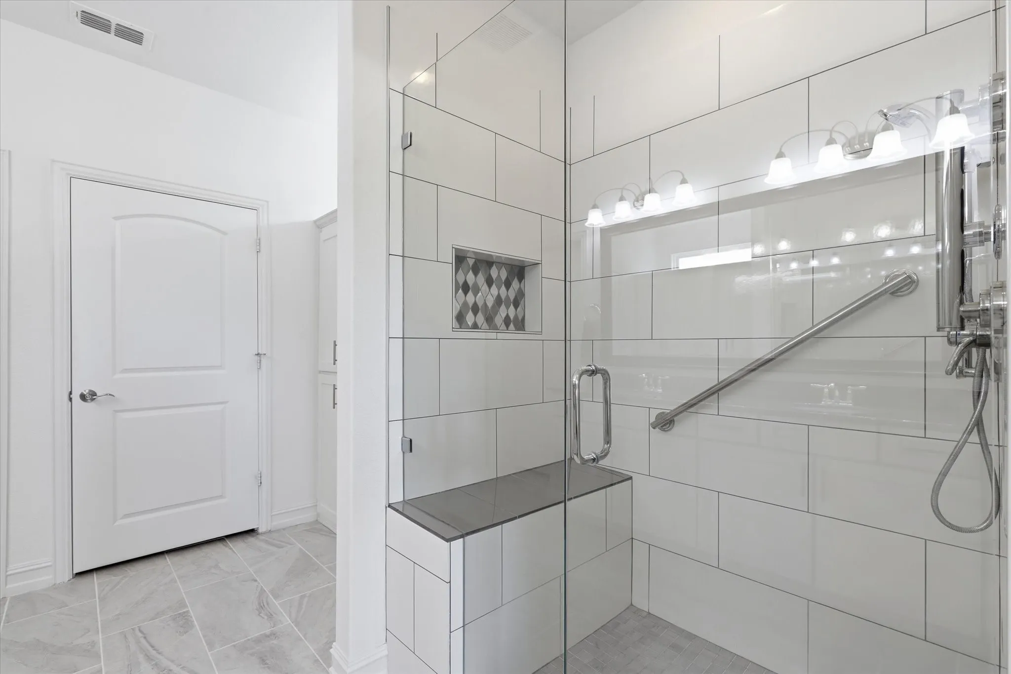 Very nice walk in shower with bench seating, grab bar, sprayer as well as shower head.