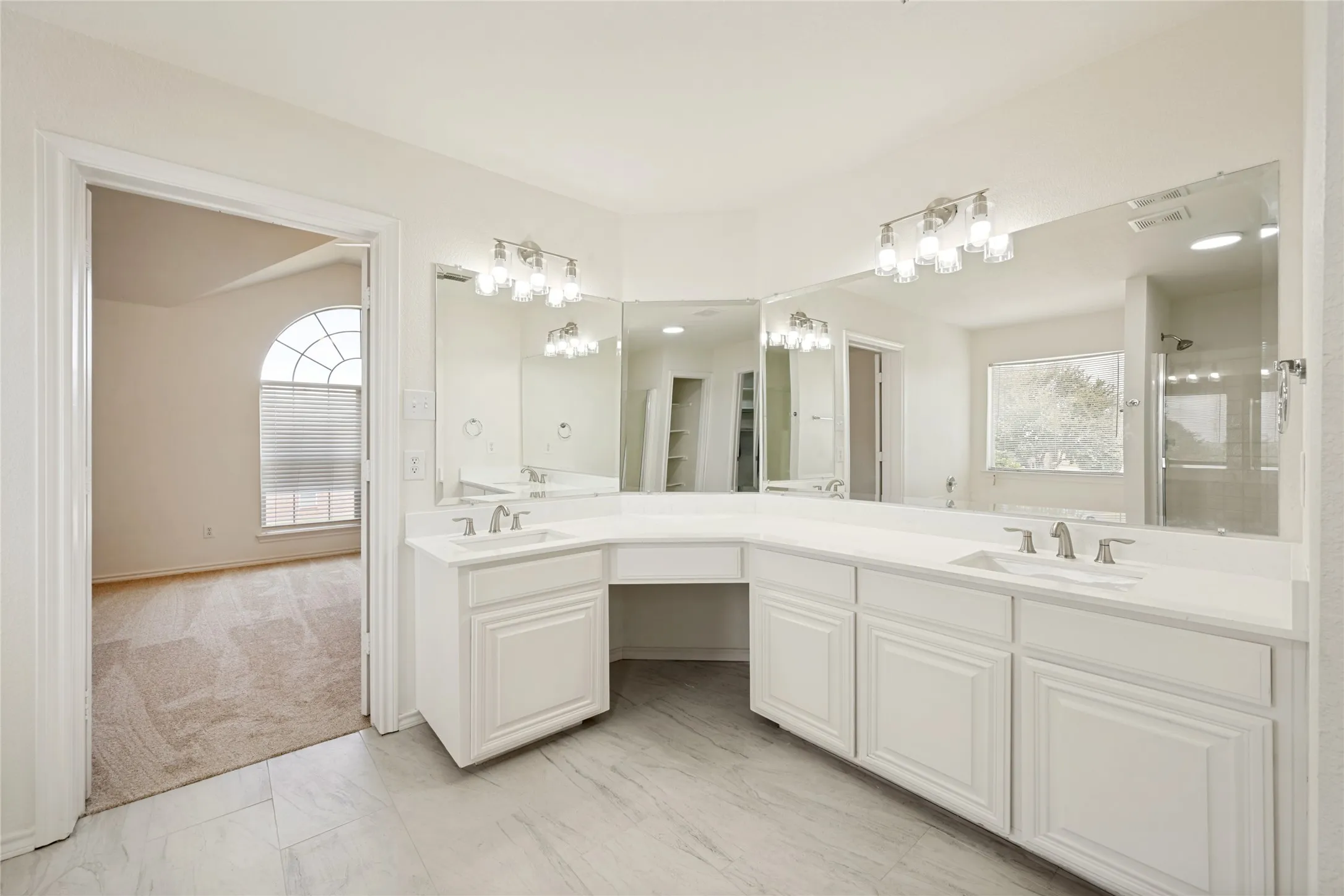 Expansive bathroom vanity featuring dual undermount sinks, white cabinetry, integrated makeup vanity, and white countertops