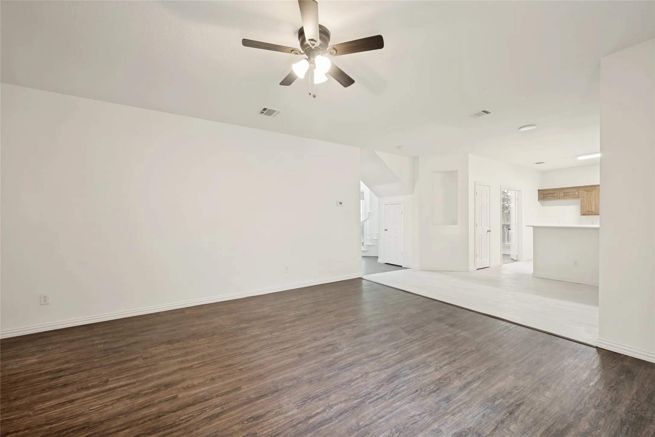 Spacious interior featuring wood-finish flooring, white walls, ceiling fan, and an open concept layout