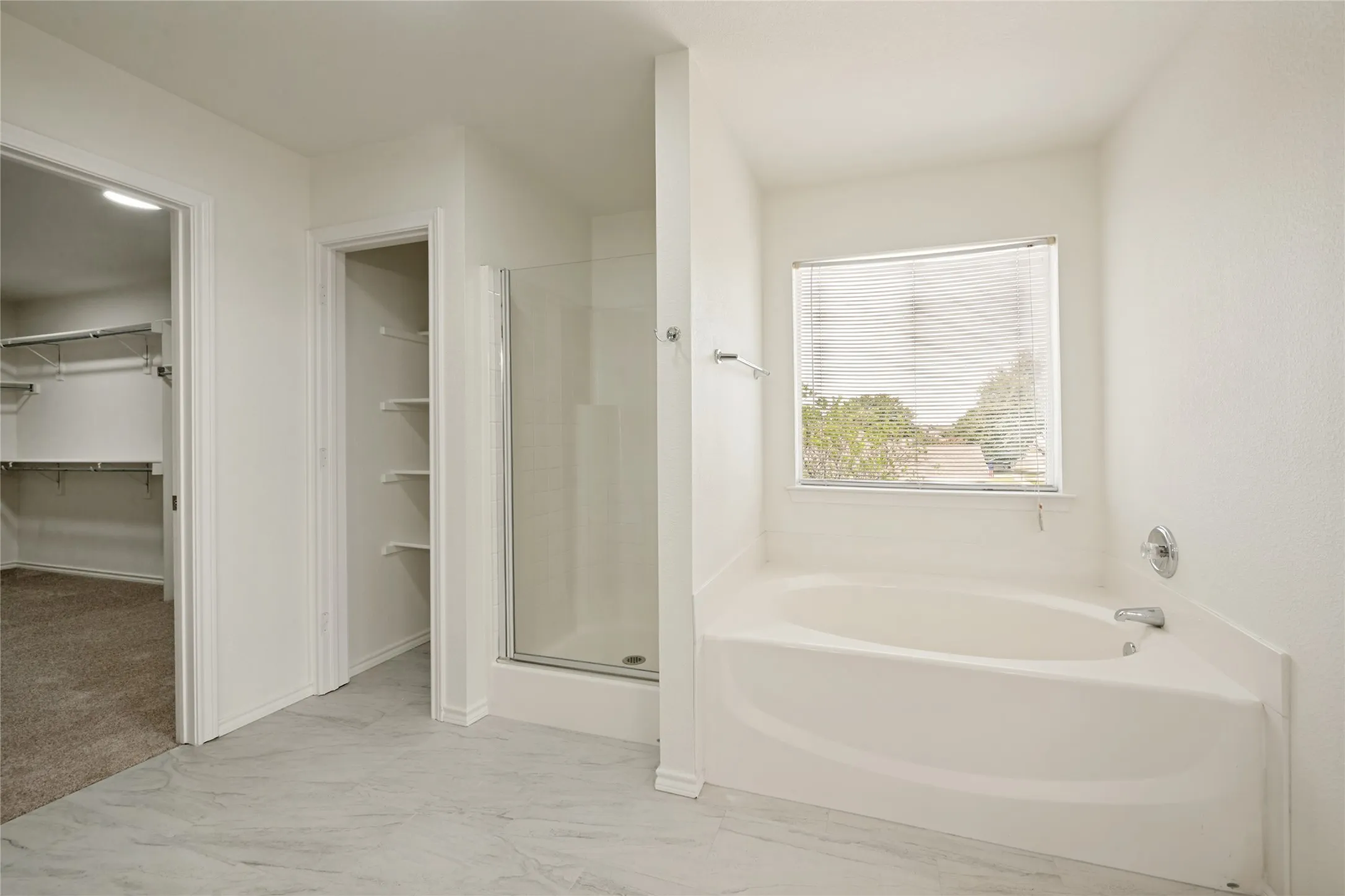 Bathroom featuring a built-in soaking tub with chrome fixtures, a separate glass-enclosed shower, and light-toned flooring