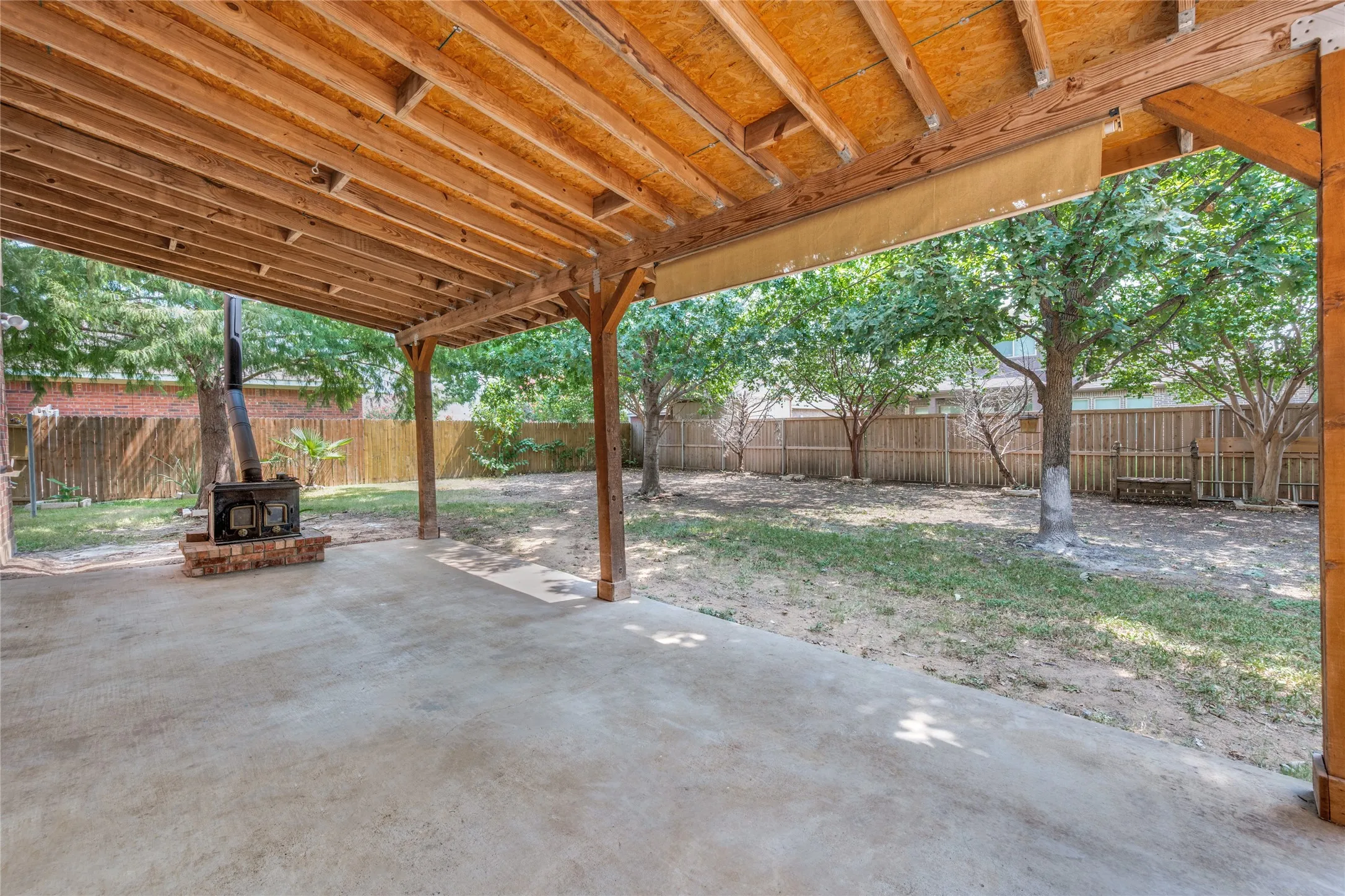 Expansive covered patio featuring a concrete slab and wood-frame overhead structure