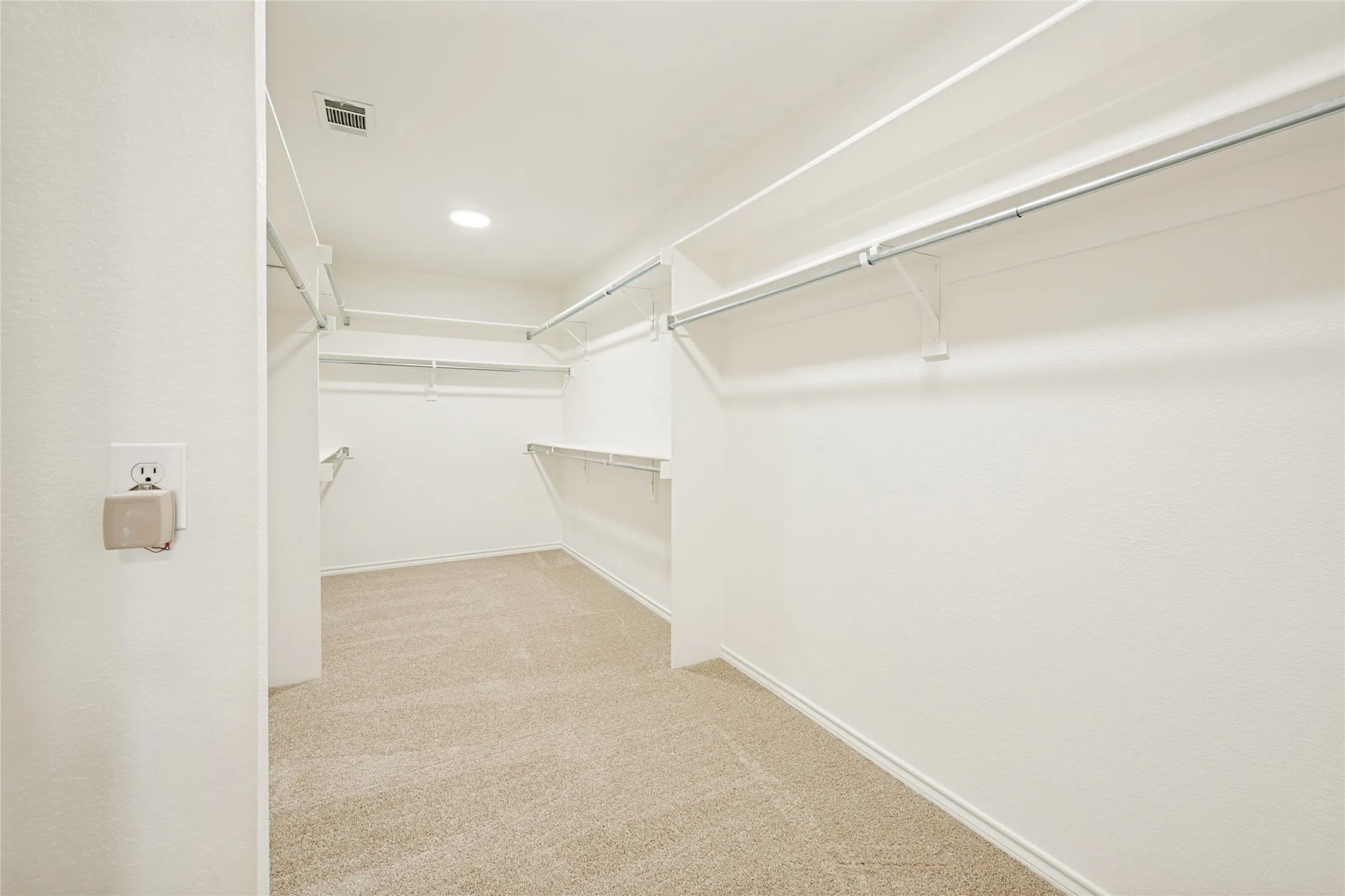 Spacious walk-in closet featuring light-toned carpeting and multiple levels of white wire shelving