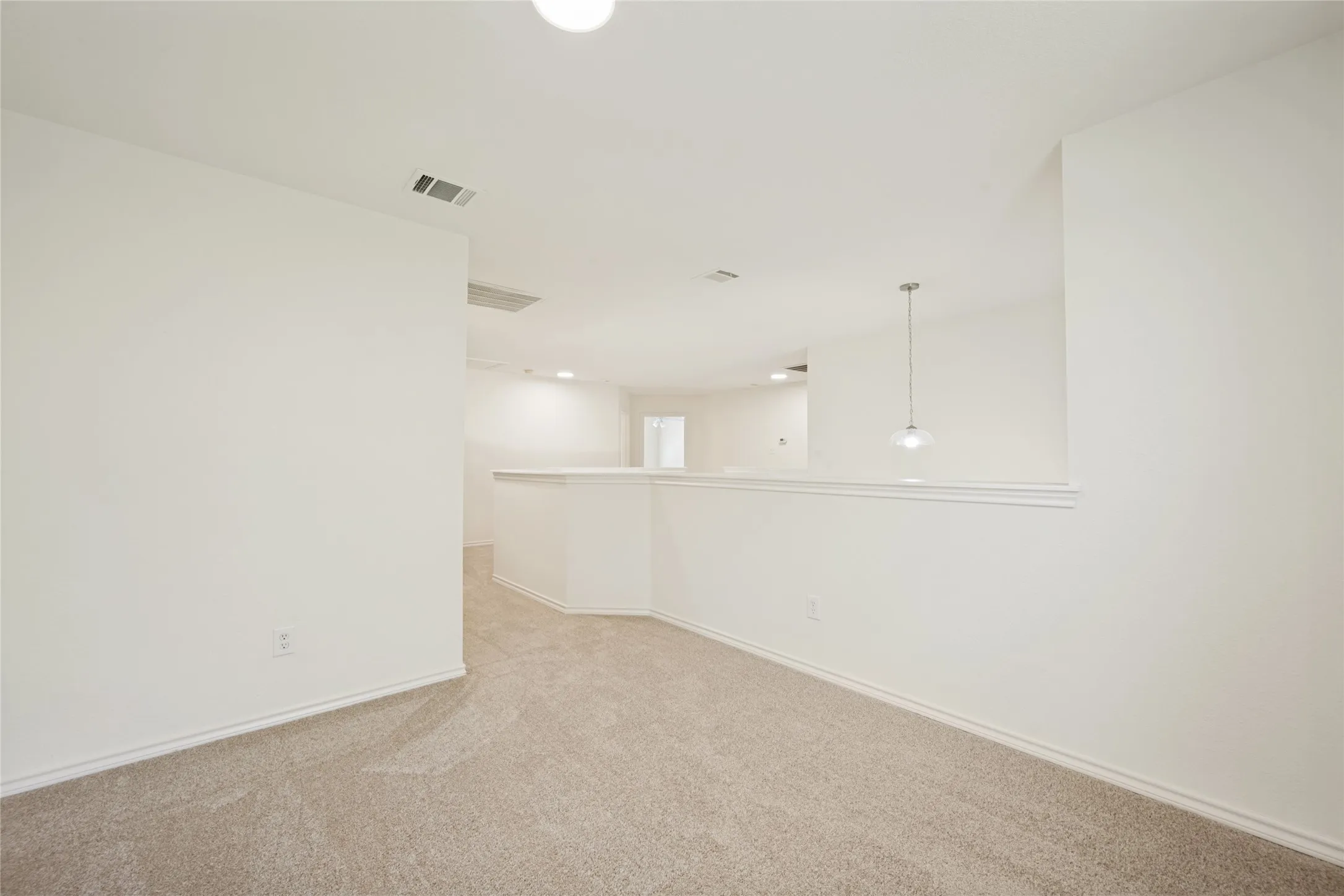 Carpeted common area featuring a neutral color palette, recessed lighting, and a modern pendant light fixture