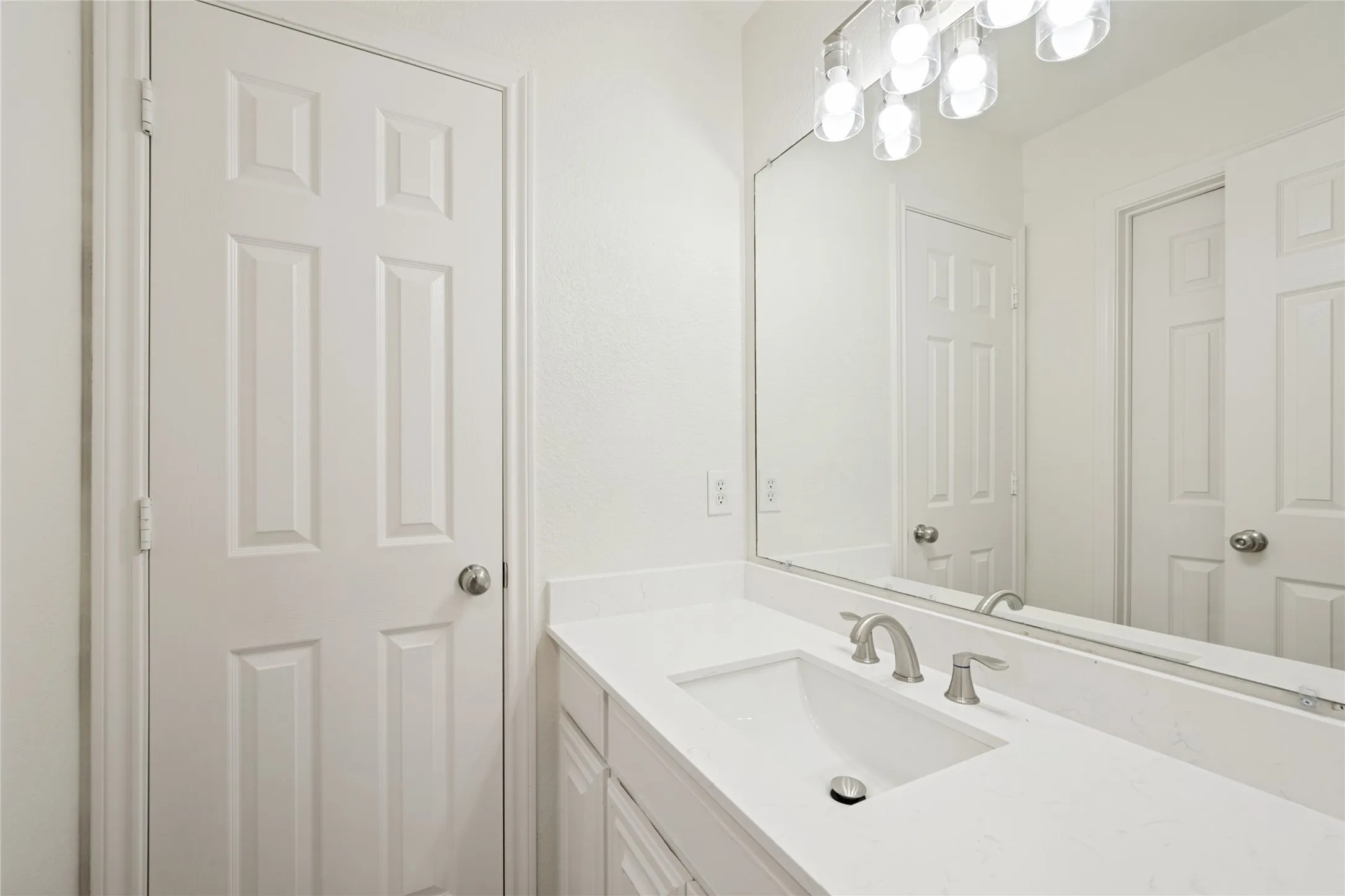 White vanity featuring an integrated rectangular sink, brushed nickel faucet, and a large wall-mounted mirror