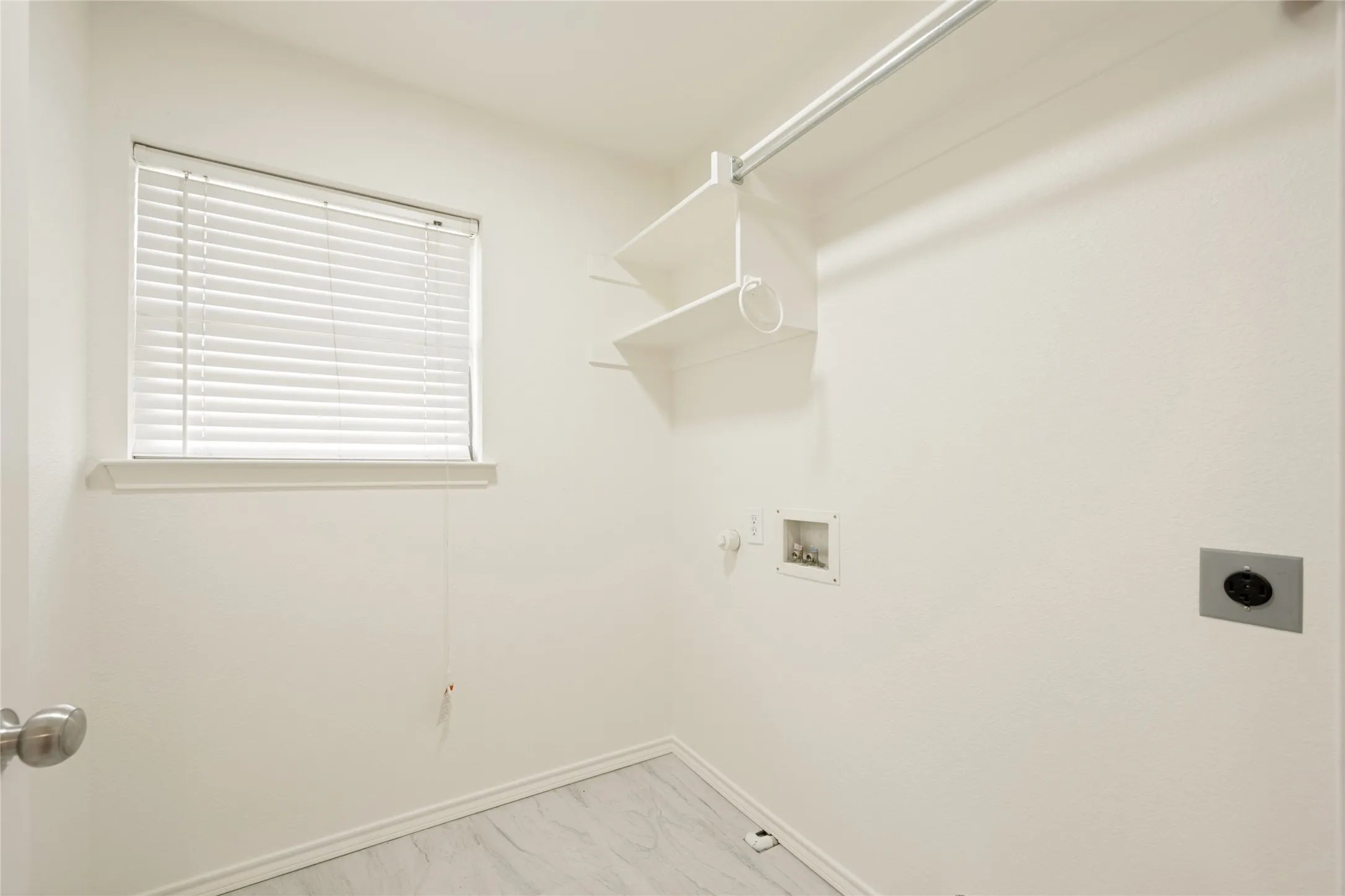 Utility space with light gray wood-finish flooring, white walls, and a window with blinds