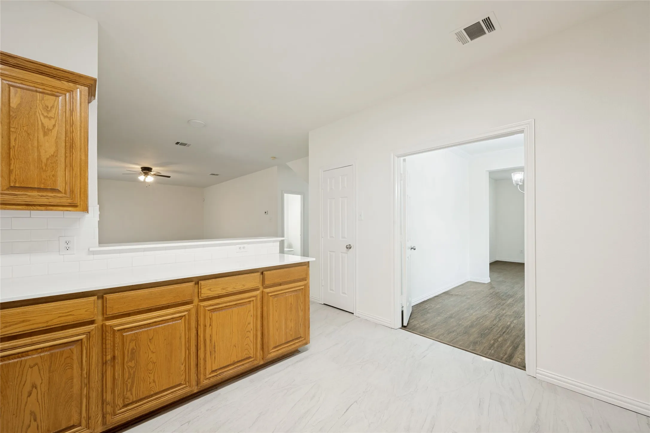 Kitchen featuring warm wood cabinetry, white countertops, white subway tile backsplash, and light wood-finish flooring