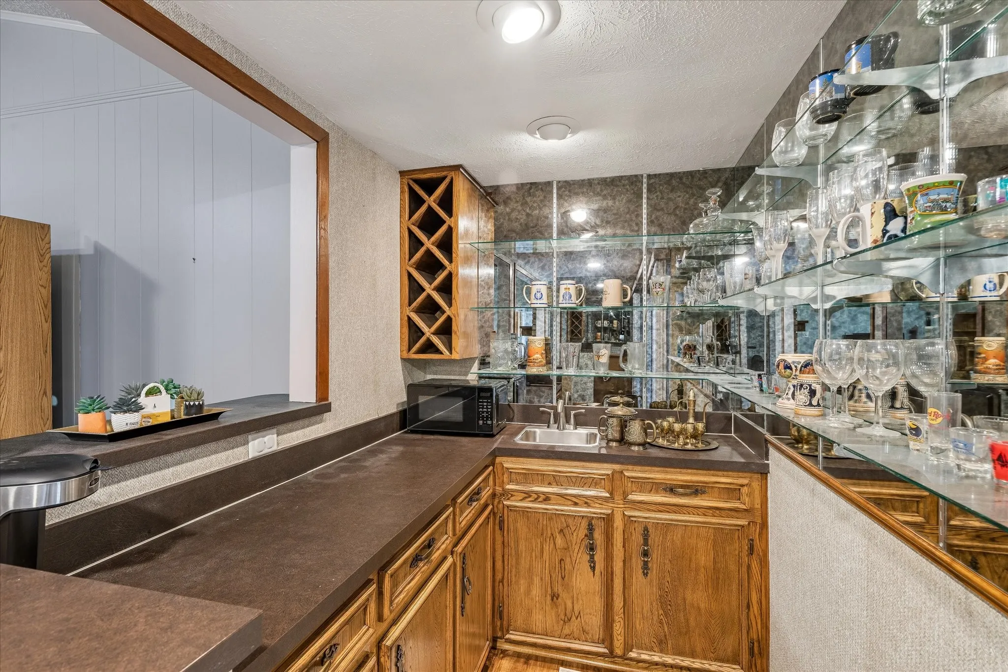Spacious kitchen featuring warm wood cabinetry with X-pattern detailing, dark laminate countertops, and stainless steel sink