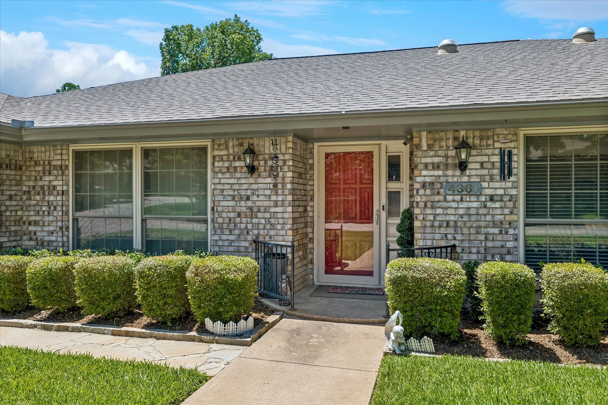 Charming brick ranch home featuring a welcoming front entrance with a red lacquered door, dual glass-panel sliding doors, and symmetrical window placement