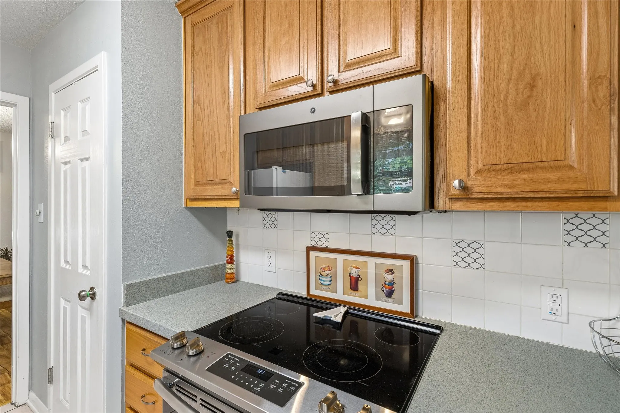 Kitchen workstation featuring a stainless steel over-the-range microwave and an electric range with a black cooktop