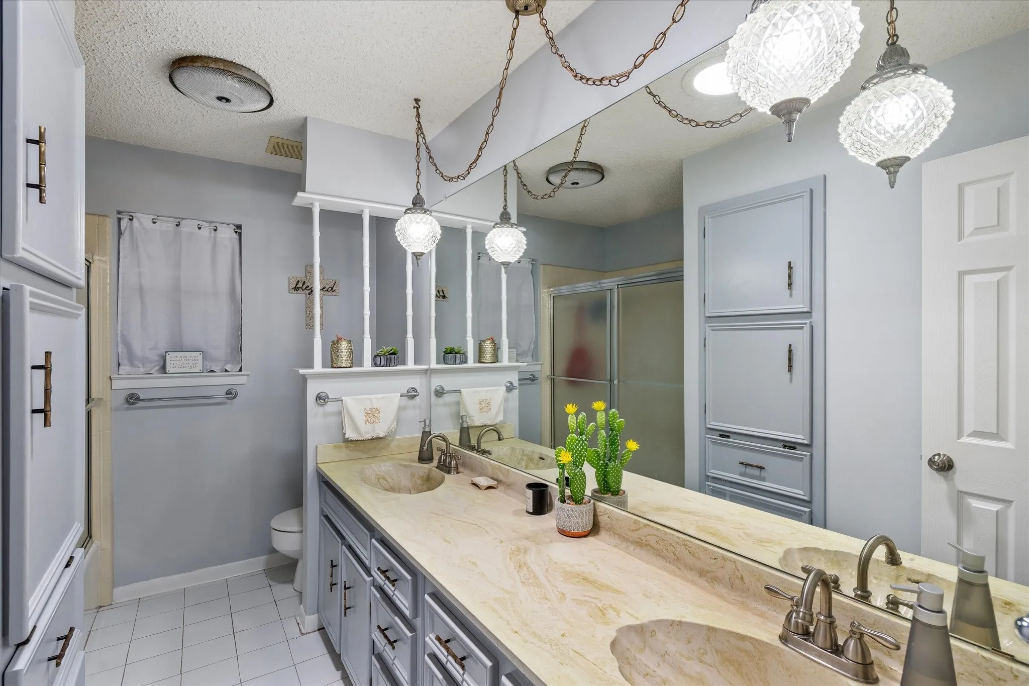 Bathroom featuring a dual vanity with integrated sinks and a stone-finish countertop, extensive mirror, built-in cabinetry, and tile flooring