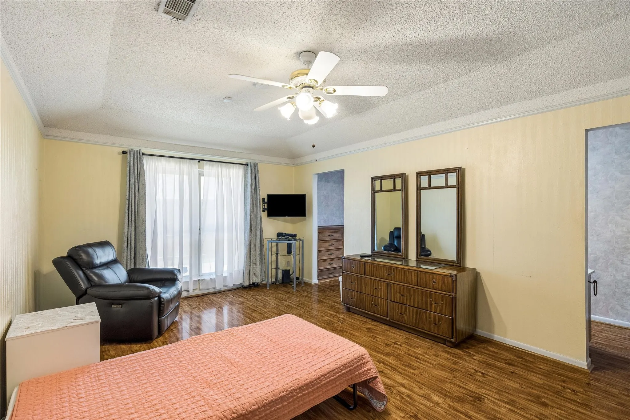Interior space featuring wood-finish flooring, crown molding, and a ceiling fan with integrated lighting