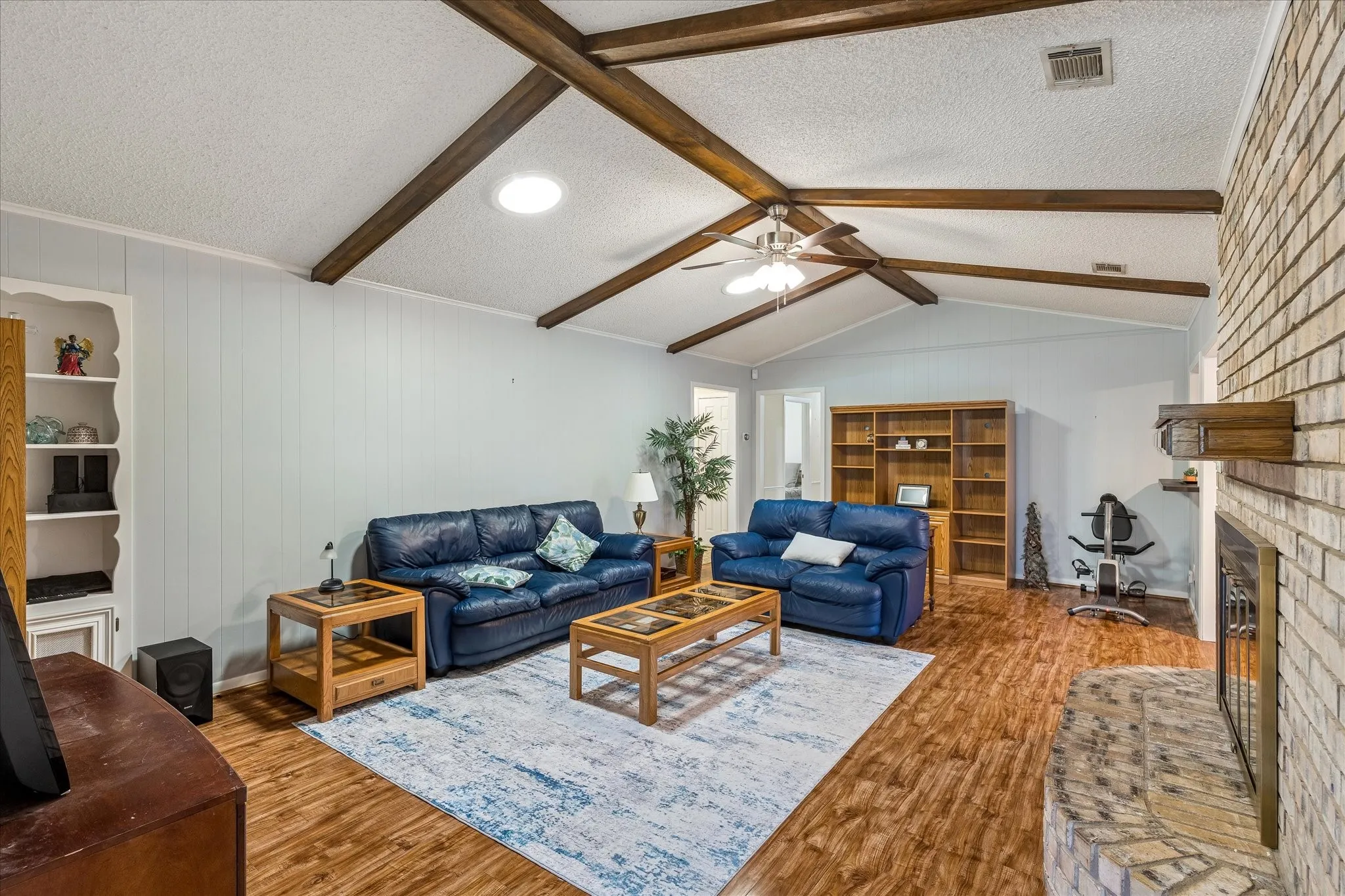 Spacious living area showcasing exposed wood beam vaulted ceilings, recessed lighting, and a light-filled layout