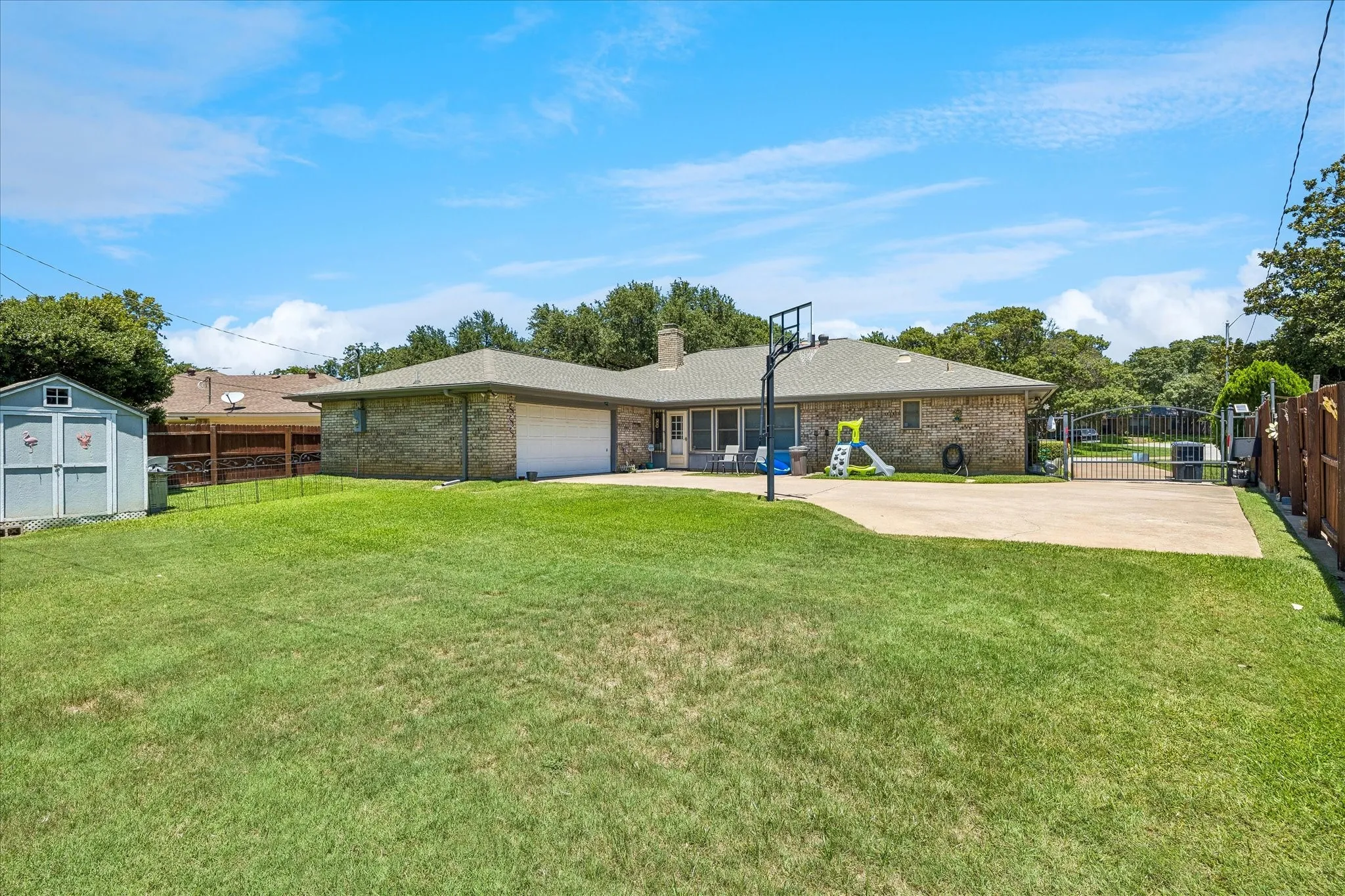 Expansive backyard featuring a manicured lawn, a detached storage shed, and a privacy fence