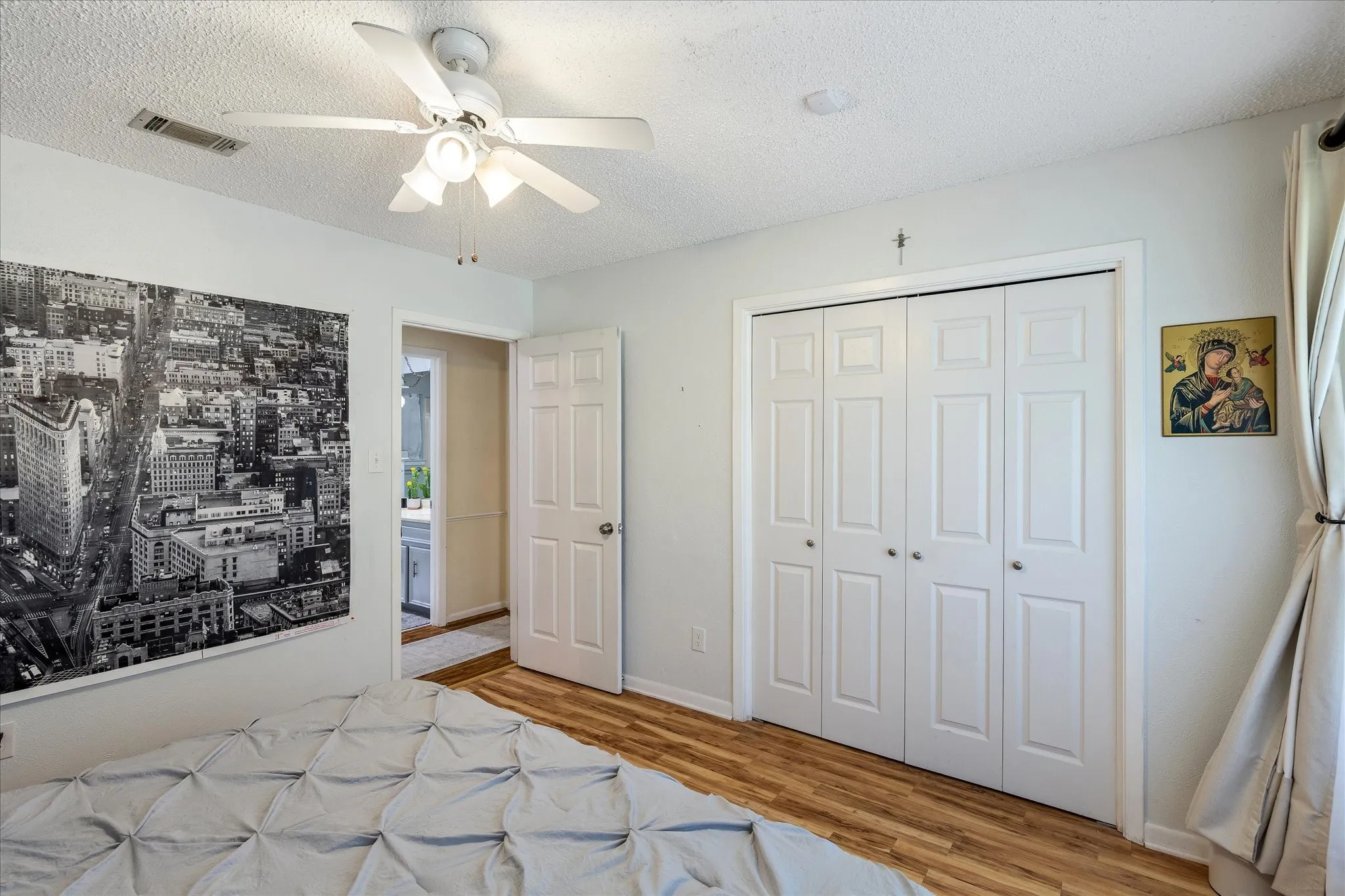 Wood-finish flooring, white bi-fold closet doors, and a ceiling fan with light fixture