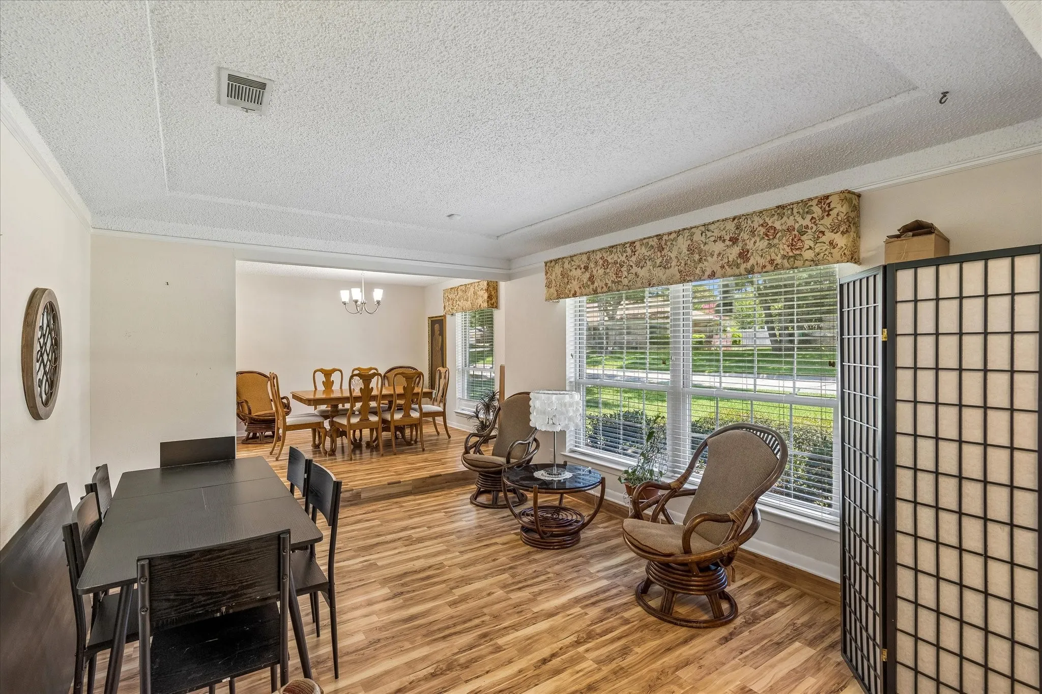 Spacious interior featuring wood-finish flooring, a tray ceiling with crown molding, and large windows with blinds