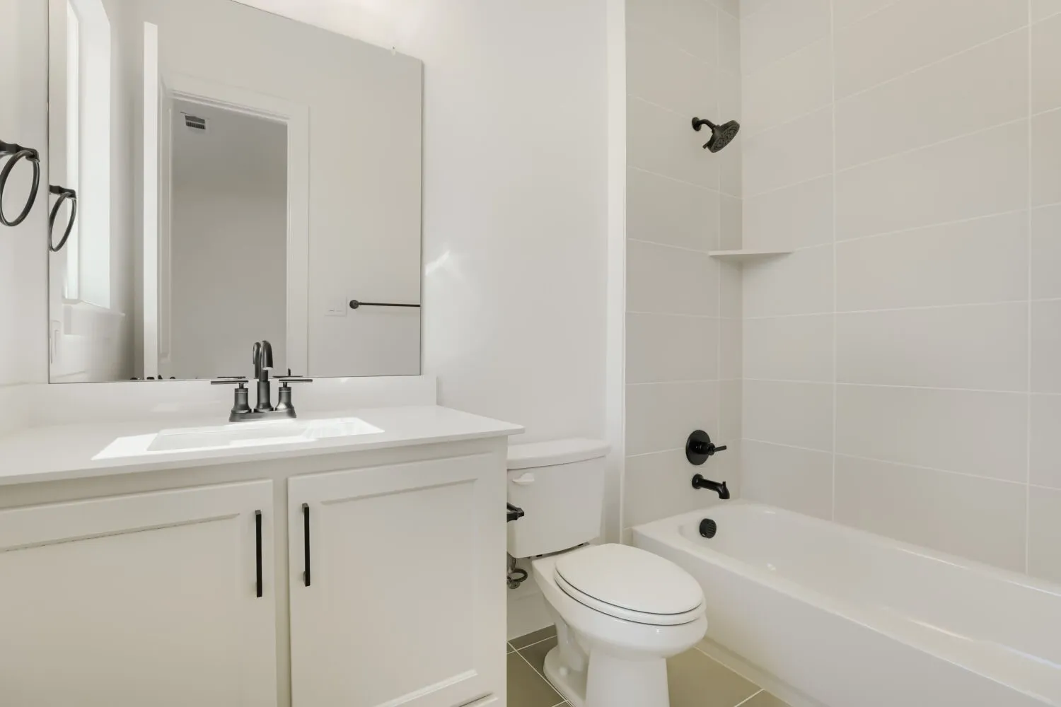 White vanity with slab cabinet doors, integrated sink, and dark-finish hardware