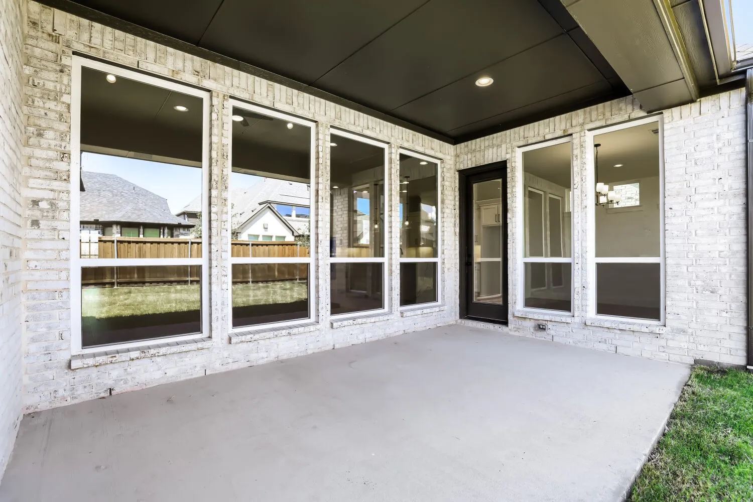 Covered patio with a concrete surface, white brick exterior, and recessed lighting