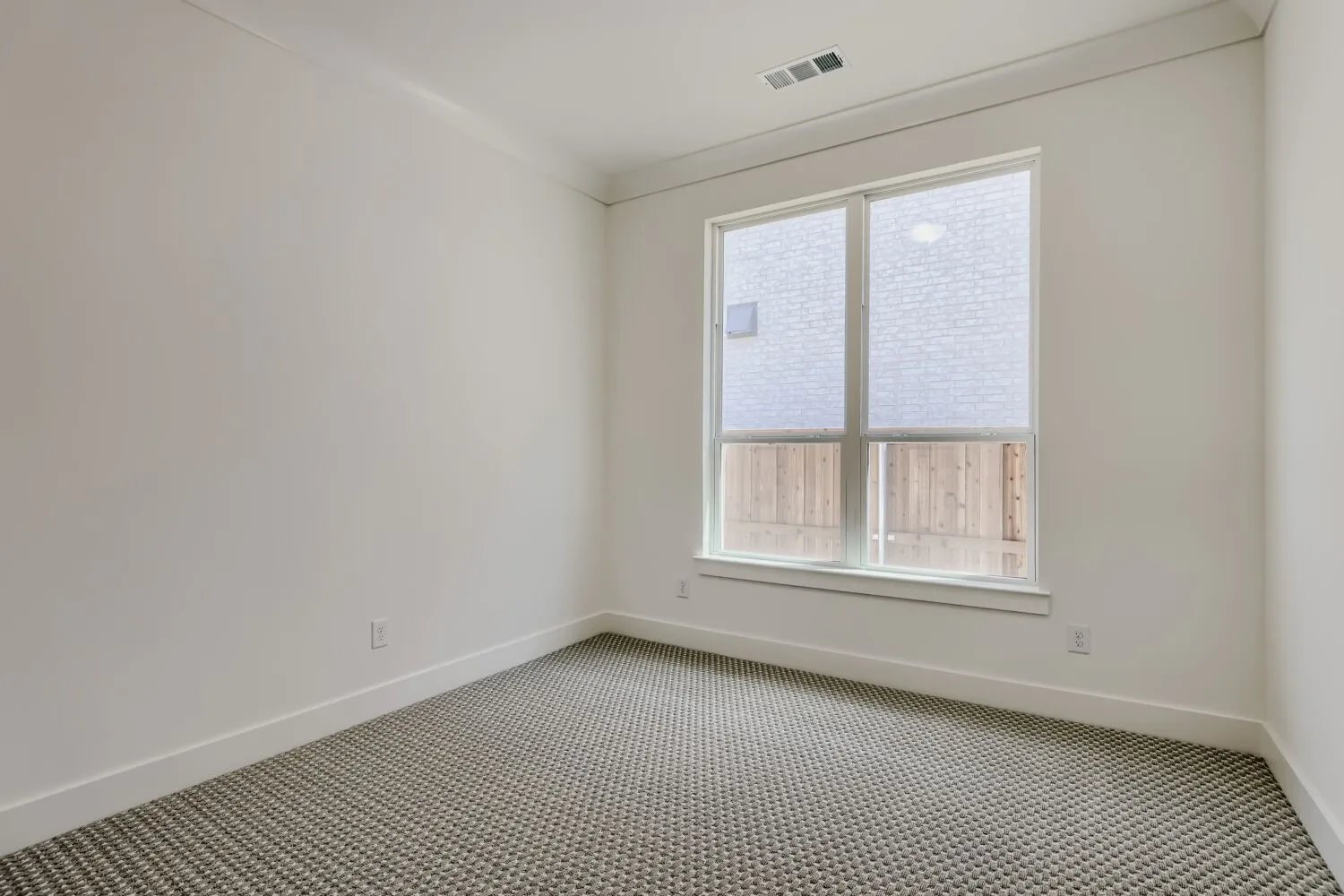 Carpeted flooring, white walls, white trim, rectangular window, and a ceiling-mounted HVAC vent