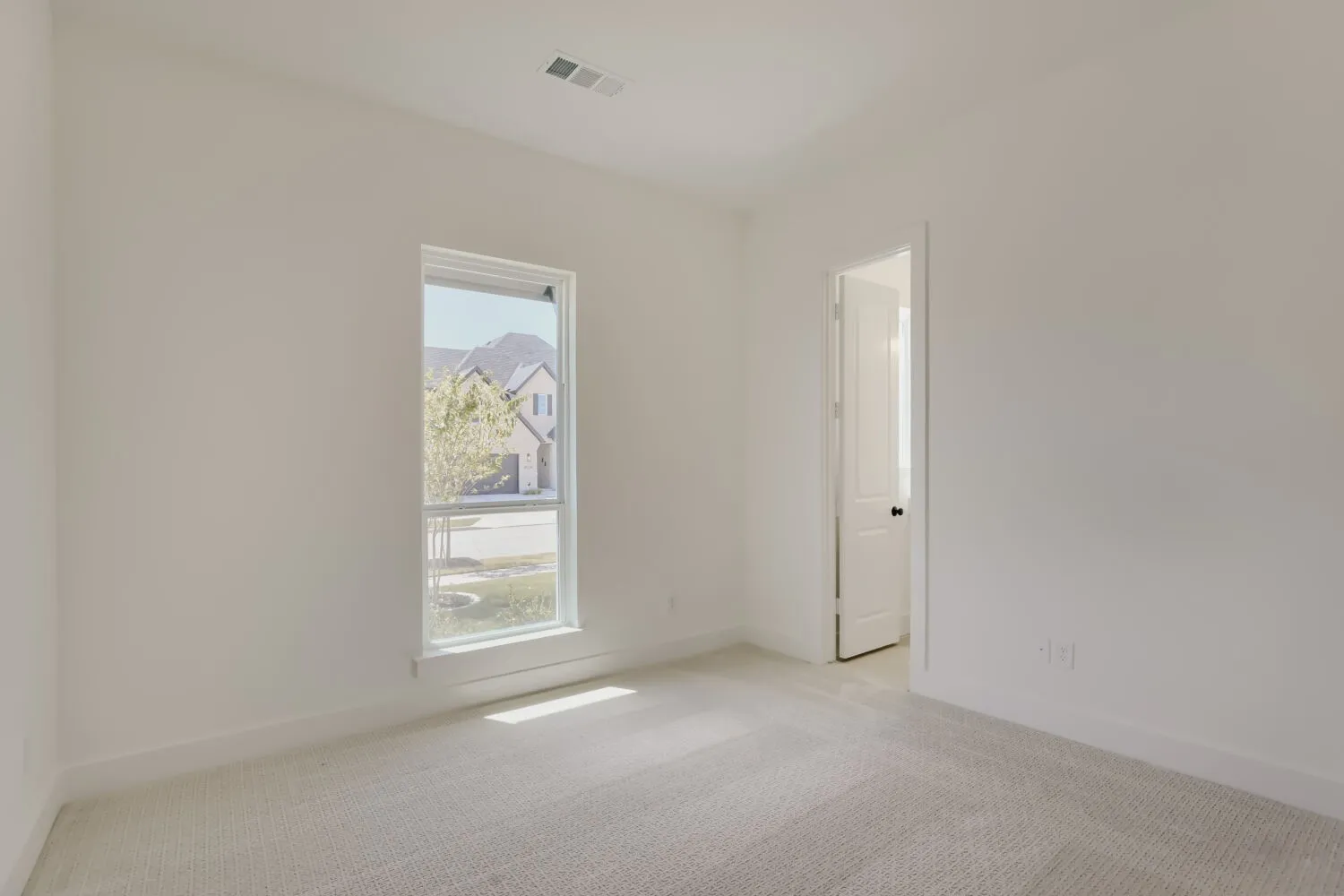 Light-toned carpet flooring, white painted walls, and a single window with white trim