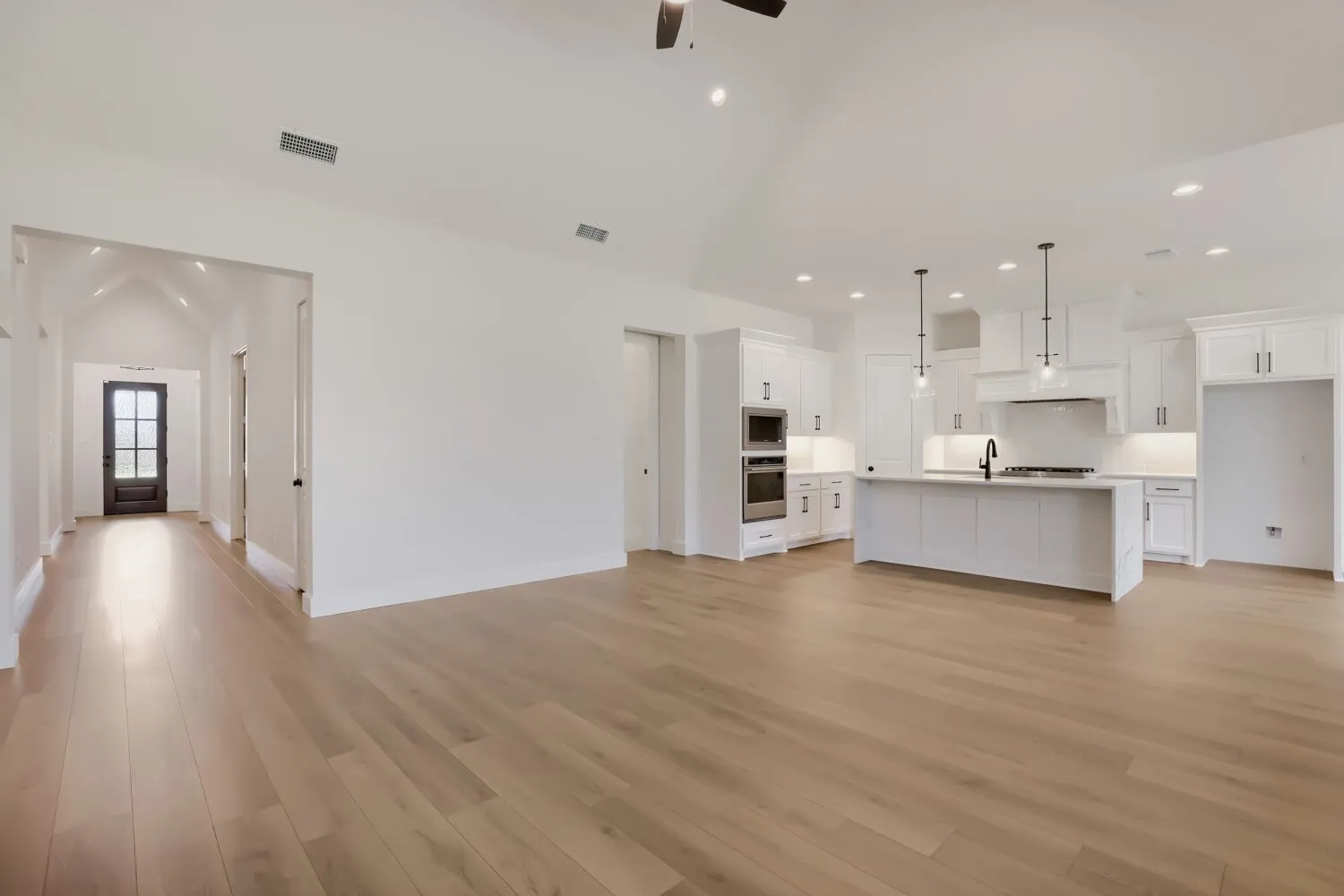 Vaulted ceilings, wood-finish flooring, and white cabinetry