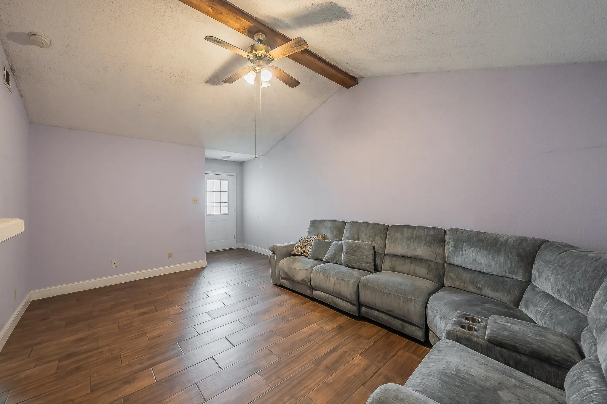 Vaulted ceiling with exposed wood beams and a ceiling fan