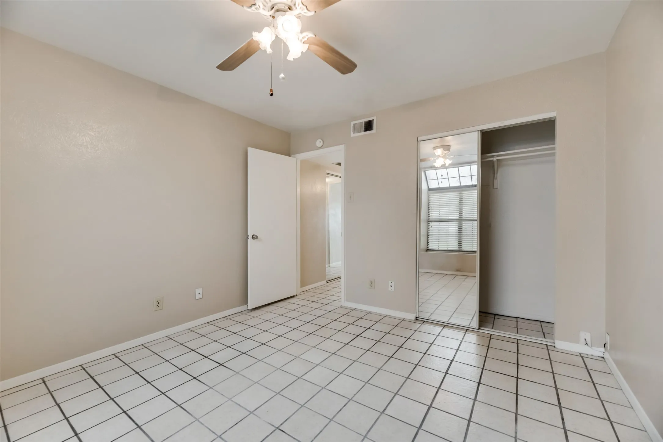 Unfurnished bedroom featuring a closet, ceiling fan, and light tile flooring