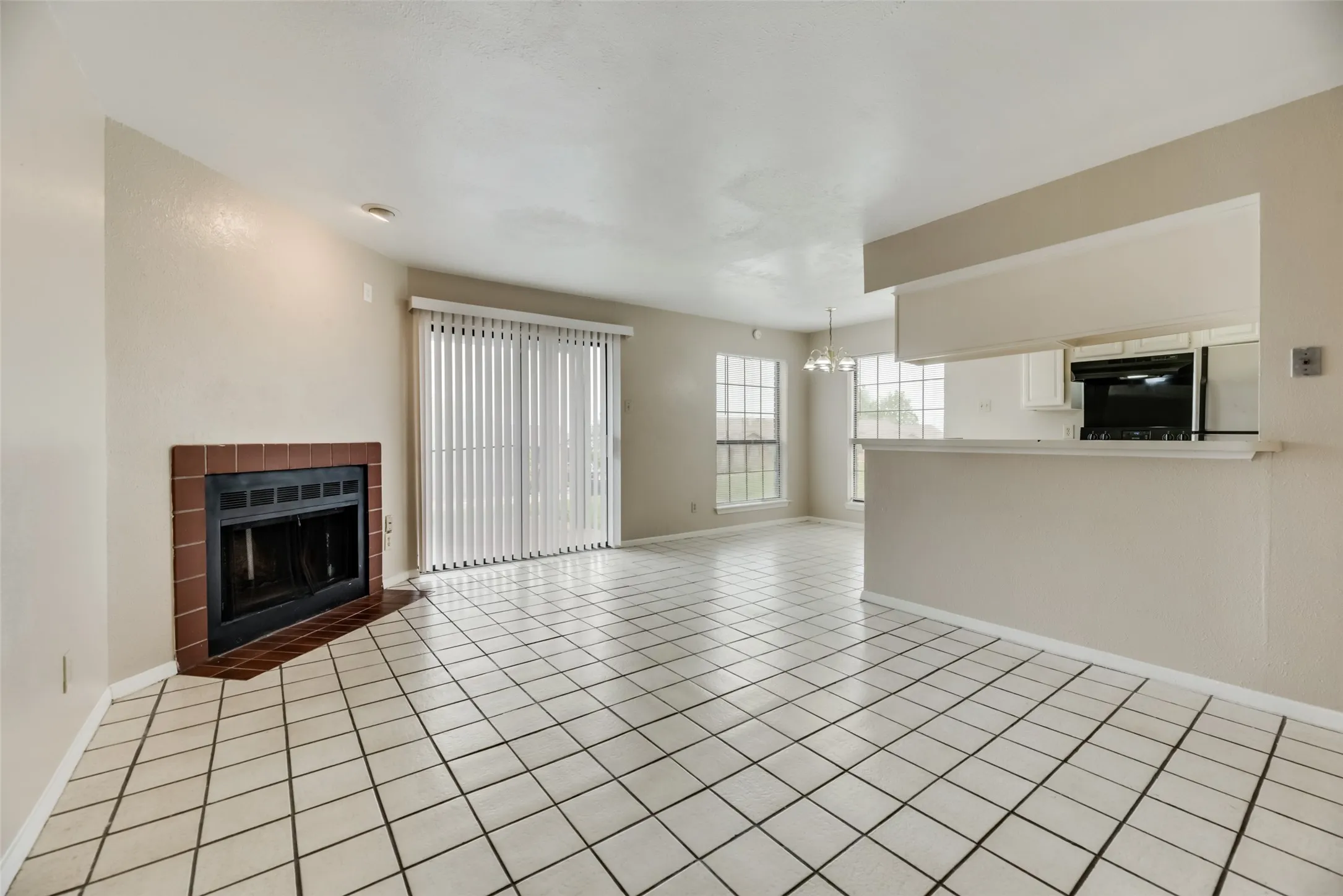 Unfurnished living room featuring an inviting chandelier, light tile floors, and a fireplace