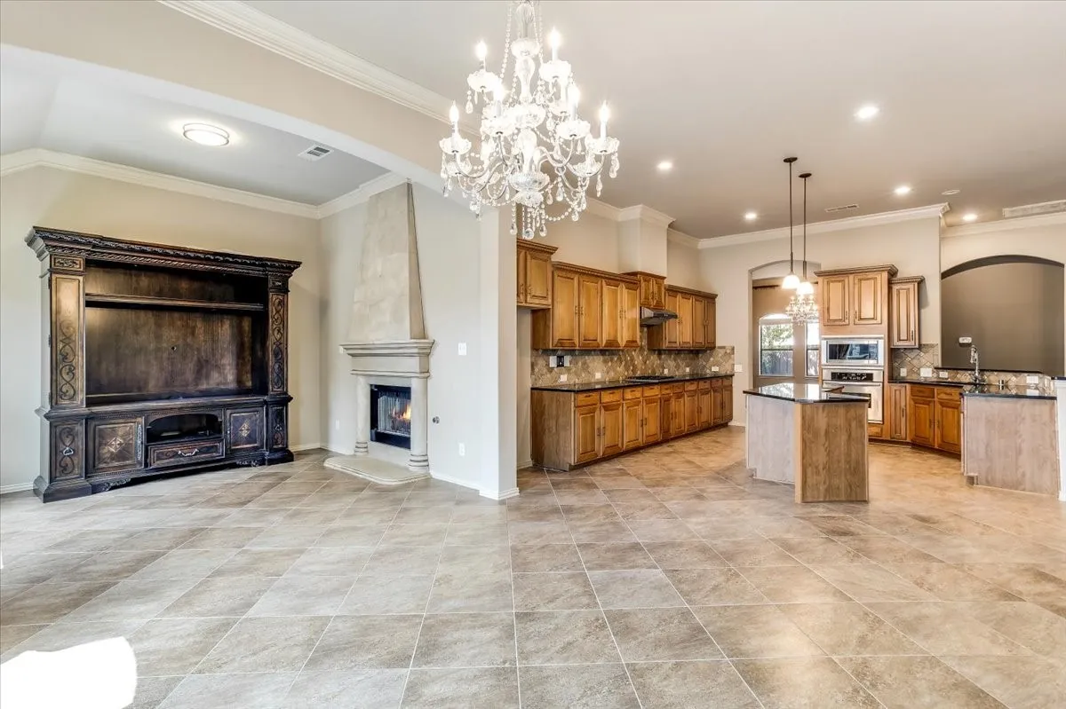 Open-concept living space featuring large format tile flooring, a built-in entertainment center, and a fireplace with a stone surround