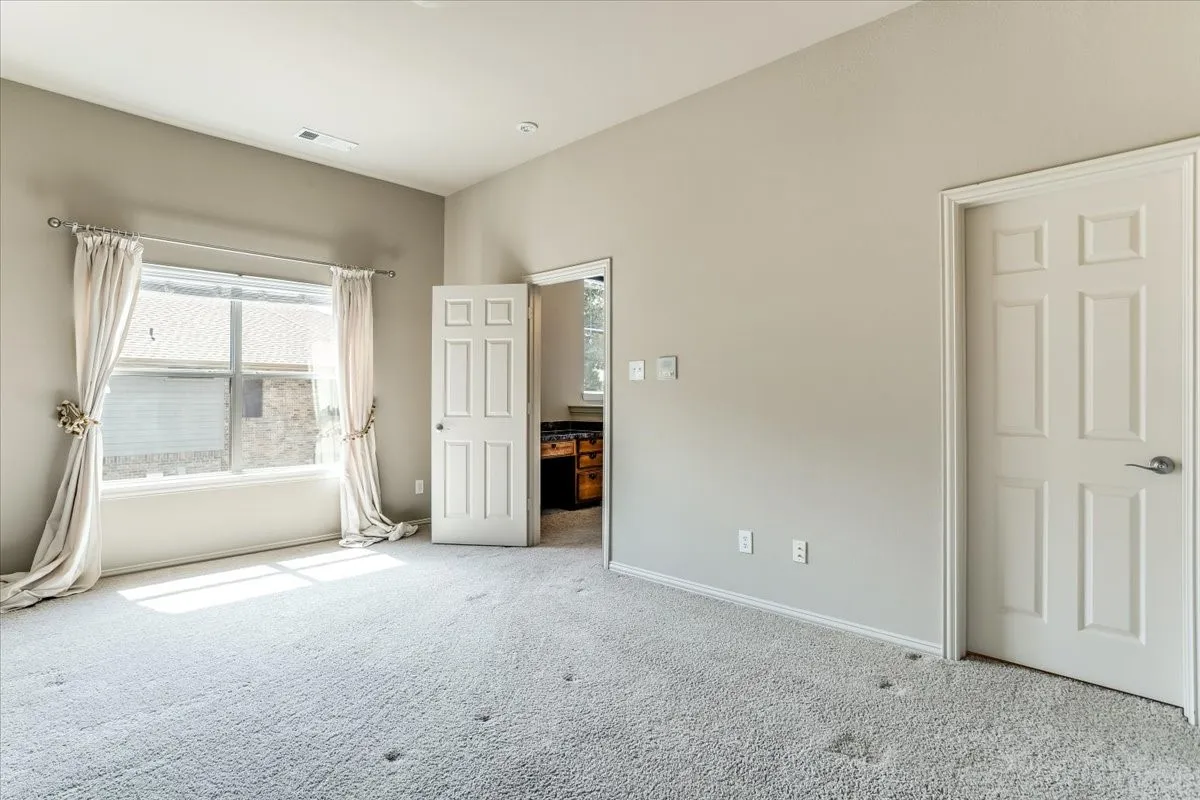 Spacious room with light gray carpeting and neutral wall tones