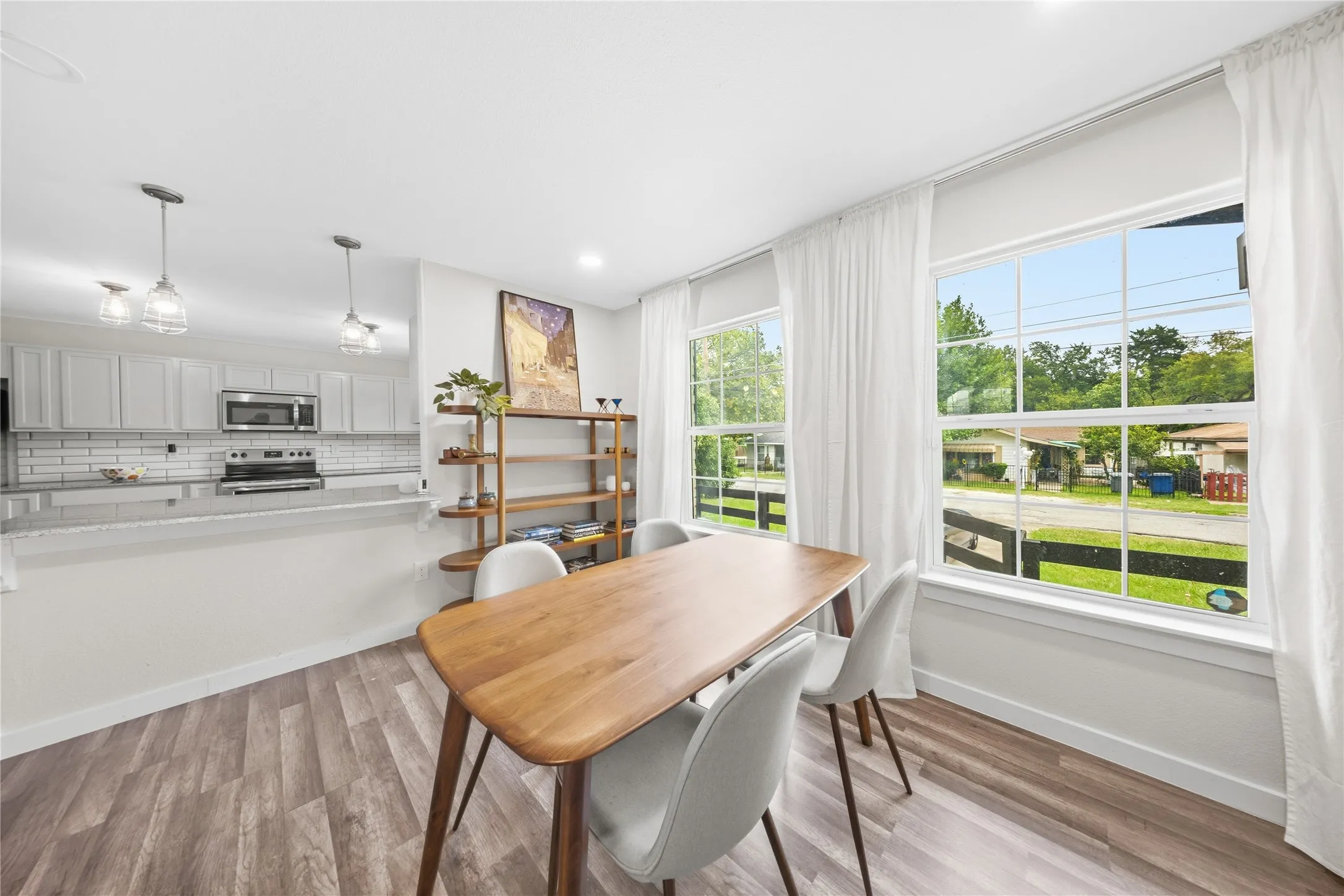 Spacious dining area featuring wood-finish flooring and two large windows with white trim