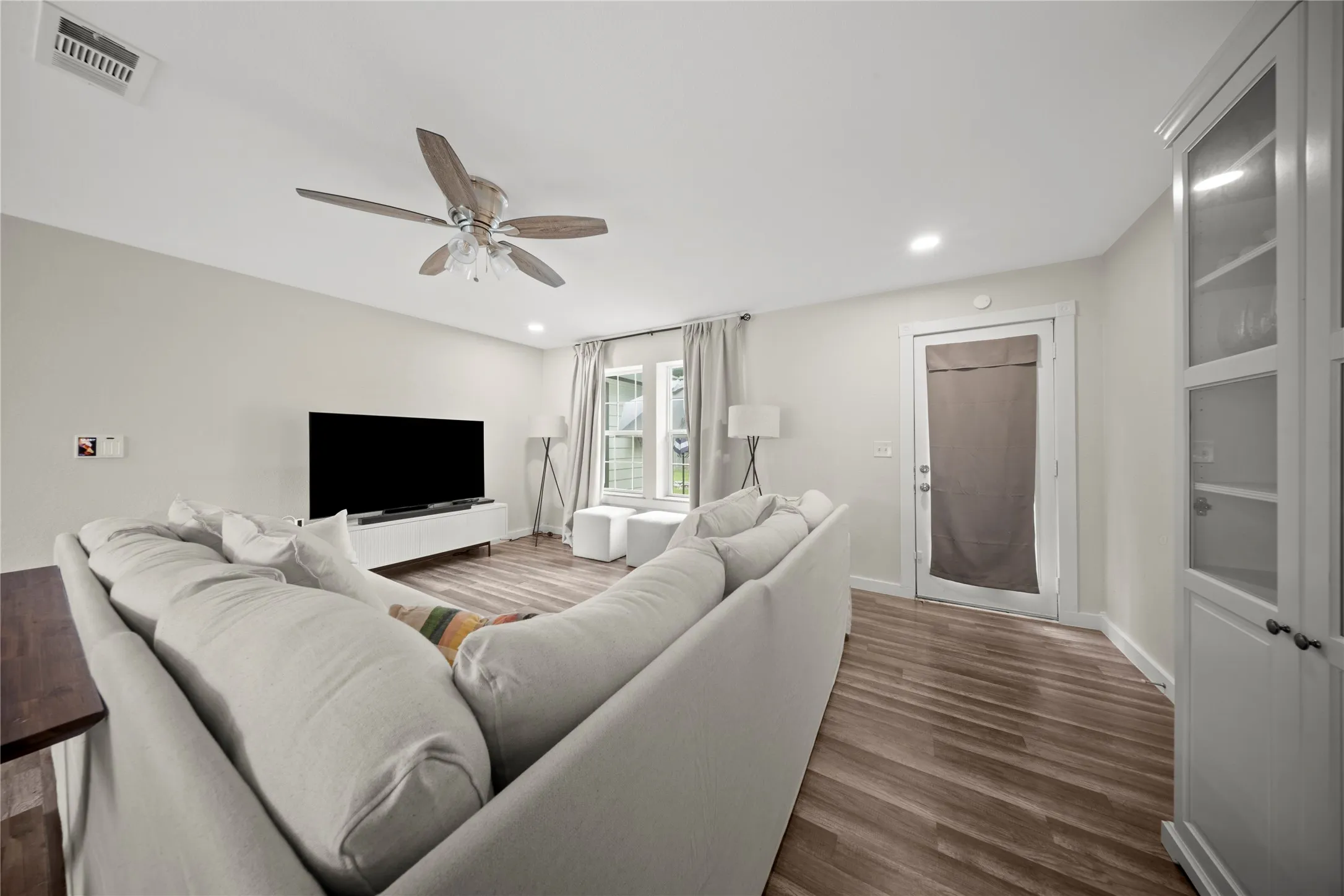 Spacious living area featuring wood-finish flooring, recessed lighting, and a ceiling fan