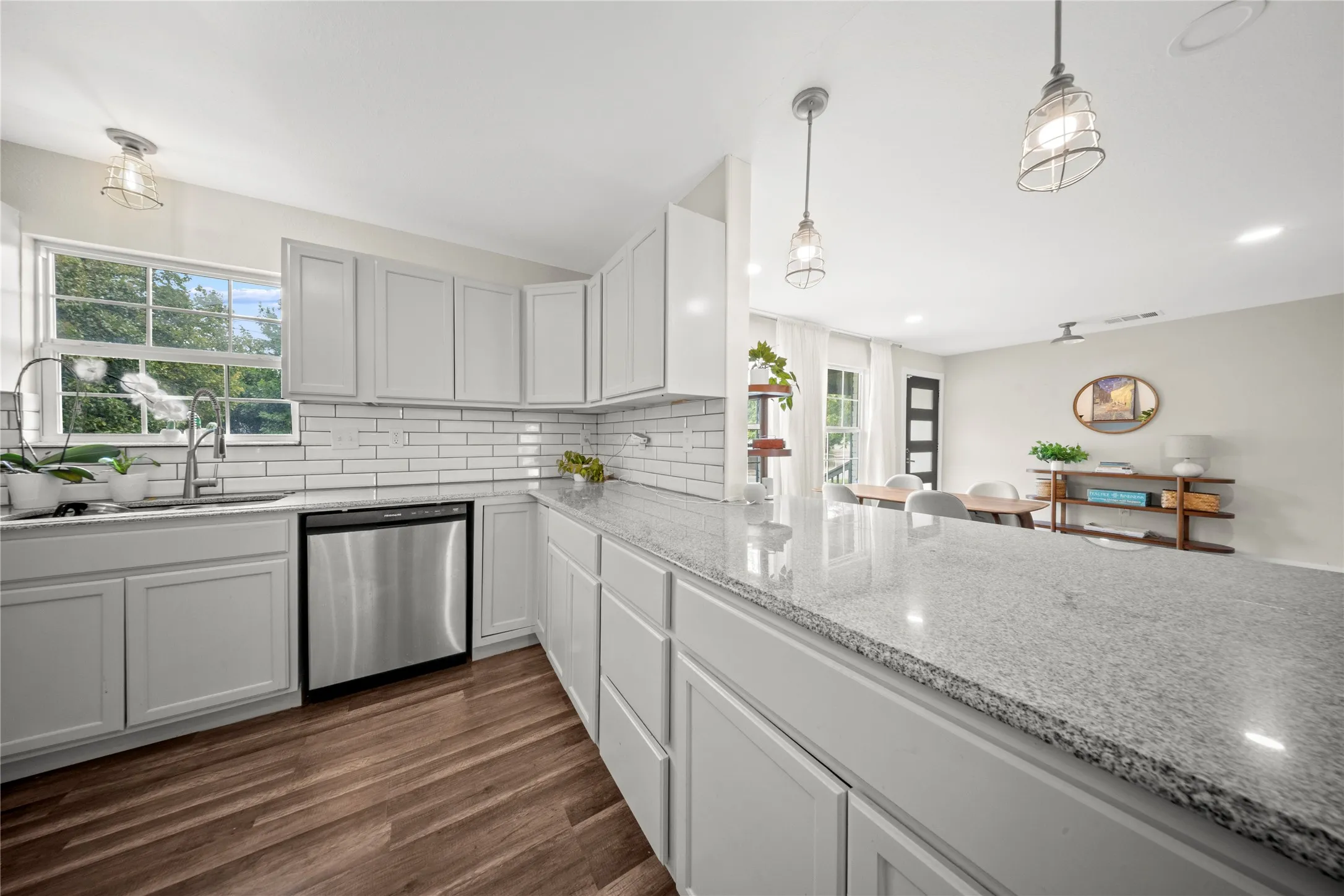 Modern kitchen featuring light gray cabinetry, stainless steel dishwasher, and a white subway tile backsplash