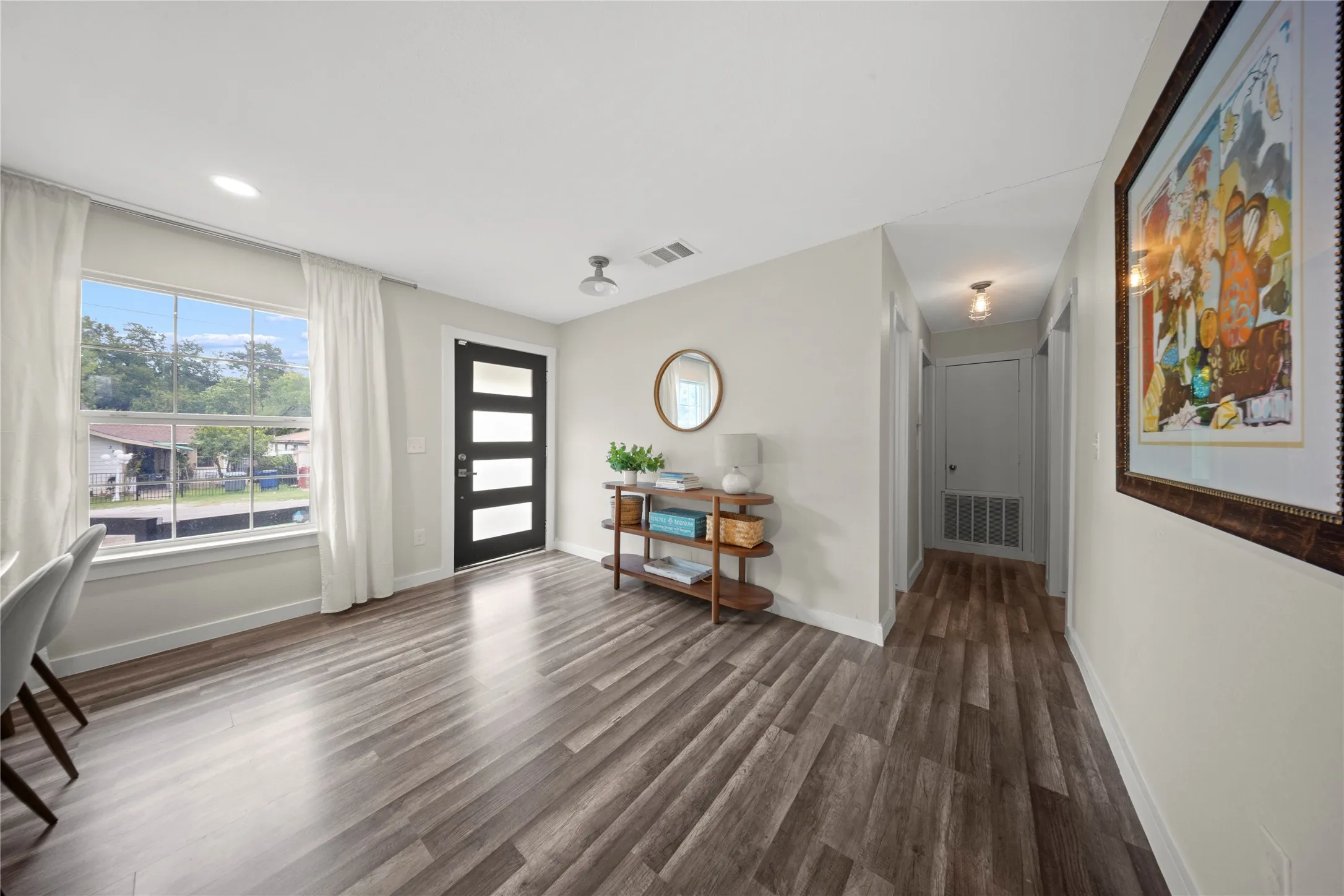 Bright and spacious entryway showcasing wood-finish flooring, recessed lighting, and clean white walls