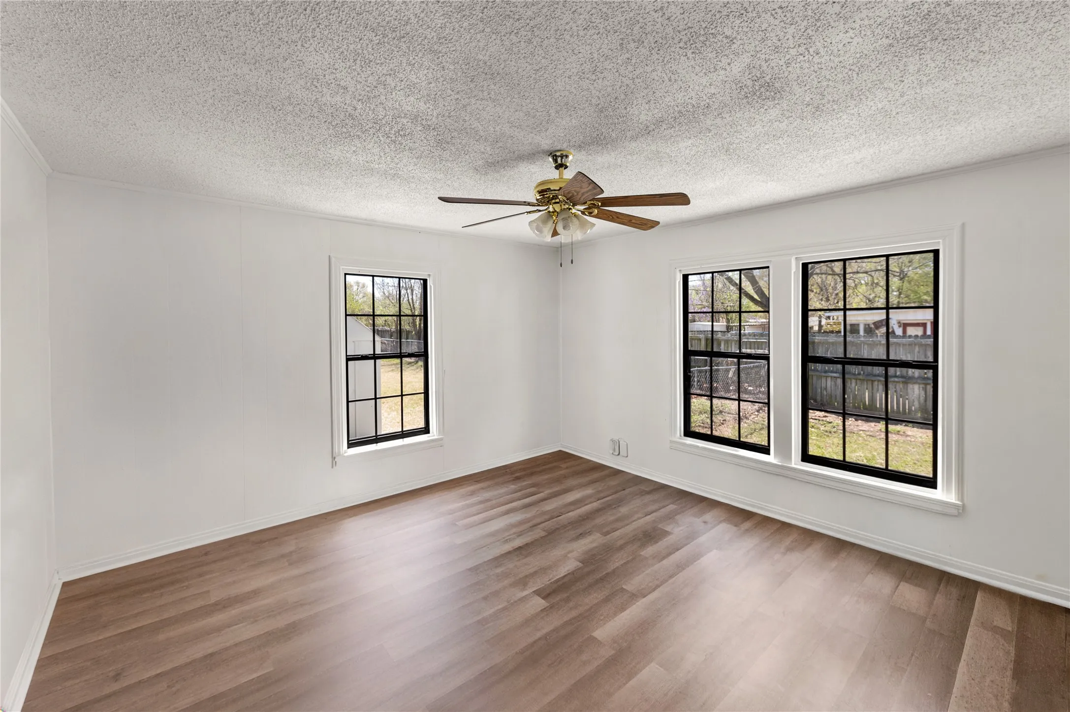 Spacious room featuring wood-finish flooring and three large windows