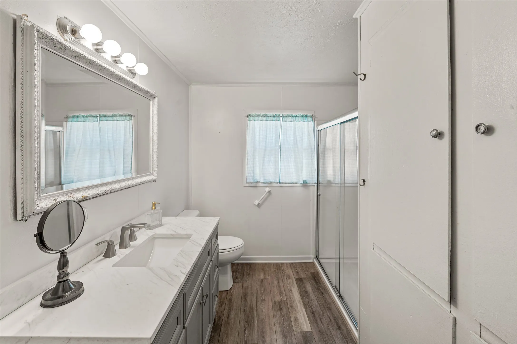 Contemporary bathroom featuring a spacious vanity with an integrated sink, a large framed mirror, and a four-bulb light fixture