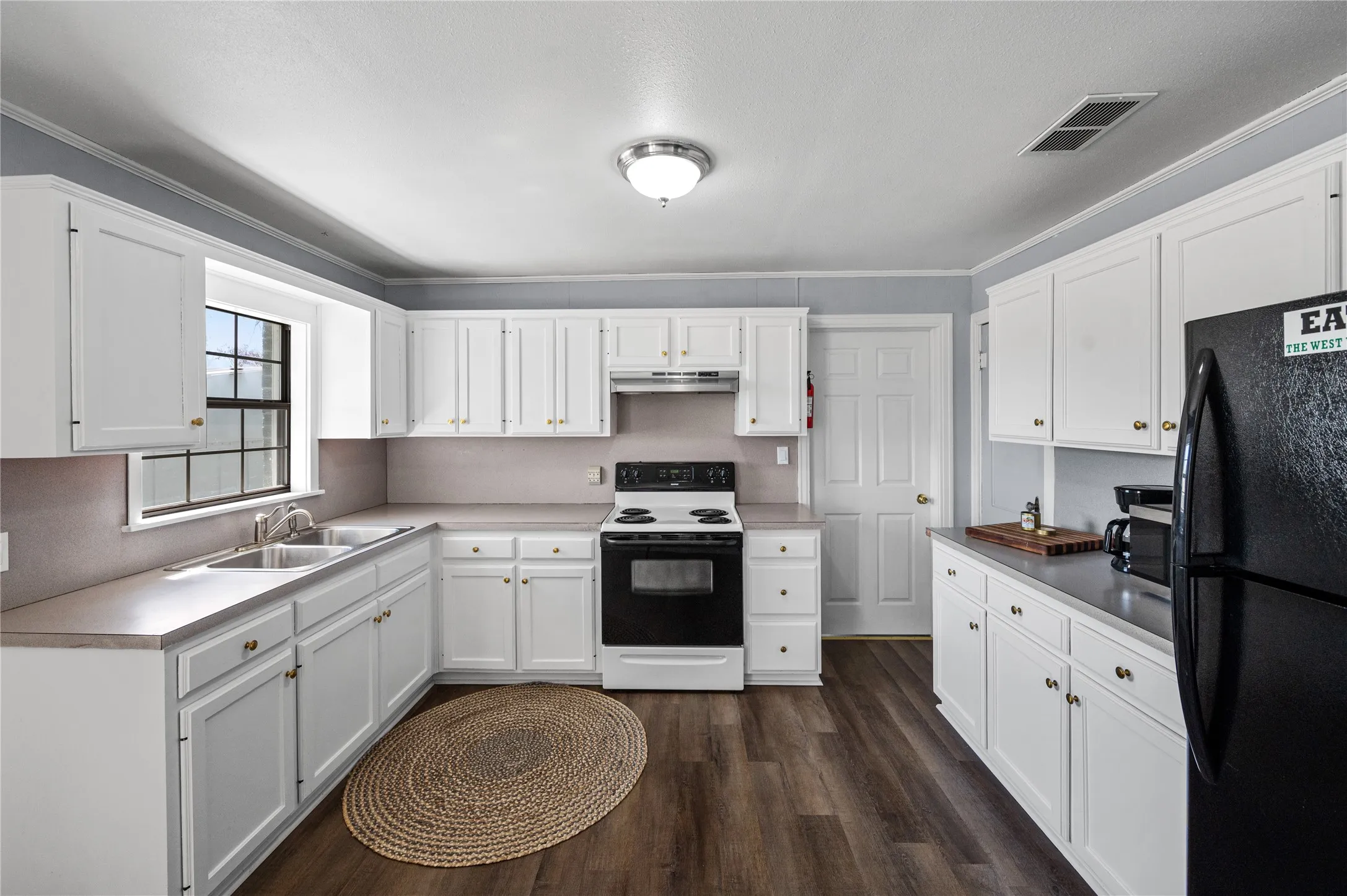 Kitchen featuring white cabinetry, laminate countertops, a black electric range, a black refrigerator, and wood-finish flooring