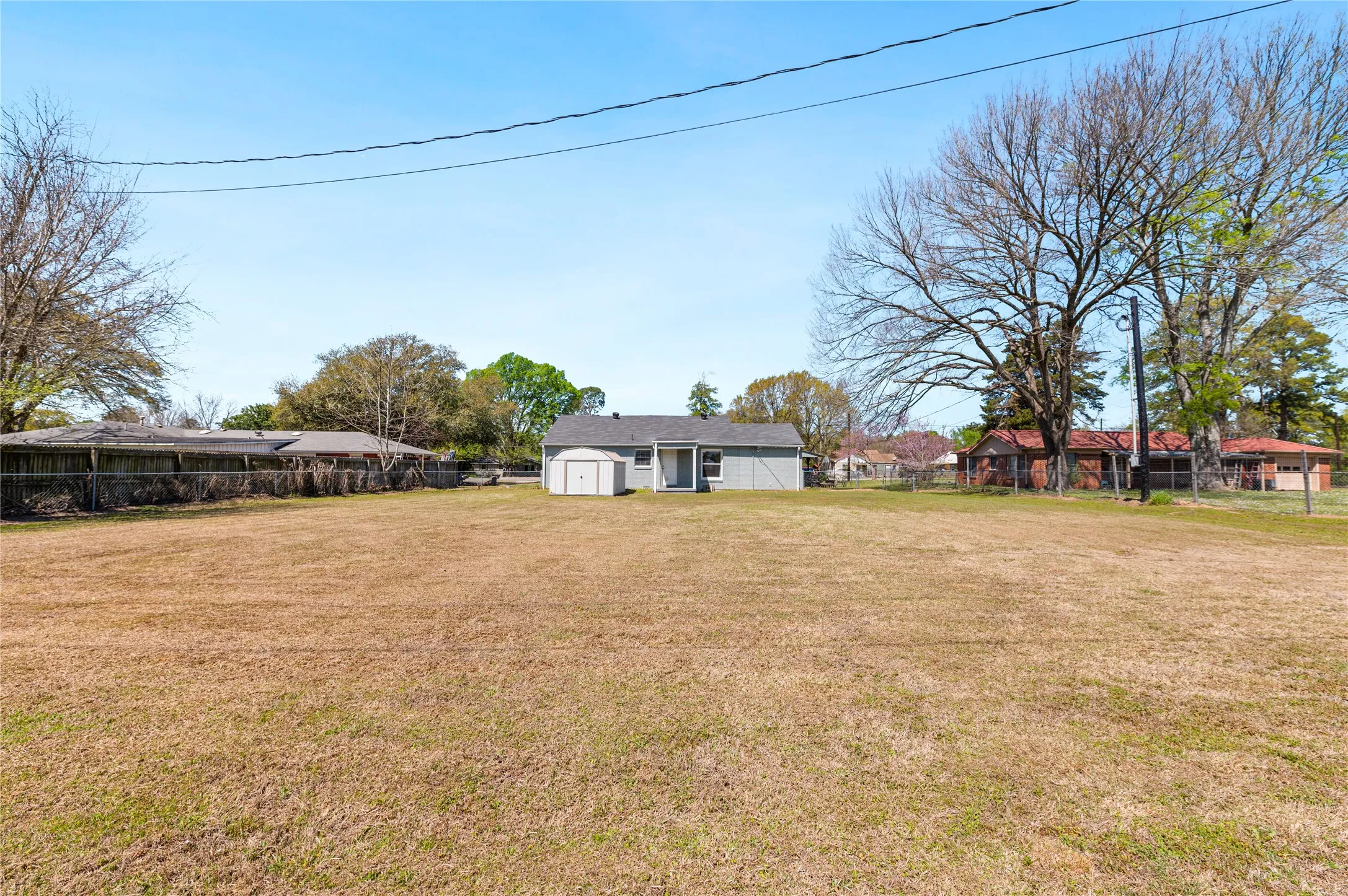 Expansive lot featuring a detached storage shed and a single-story residence with a gray exterior