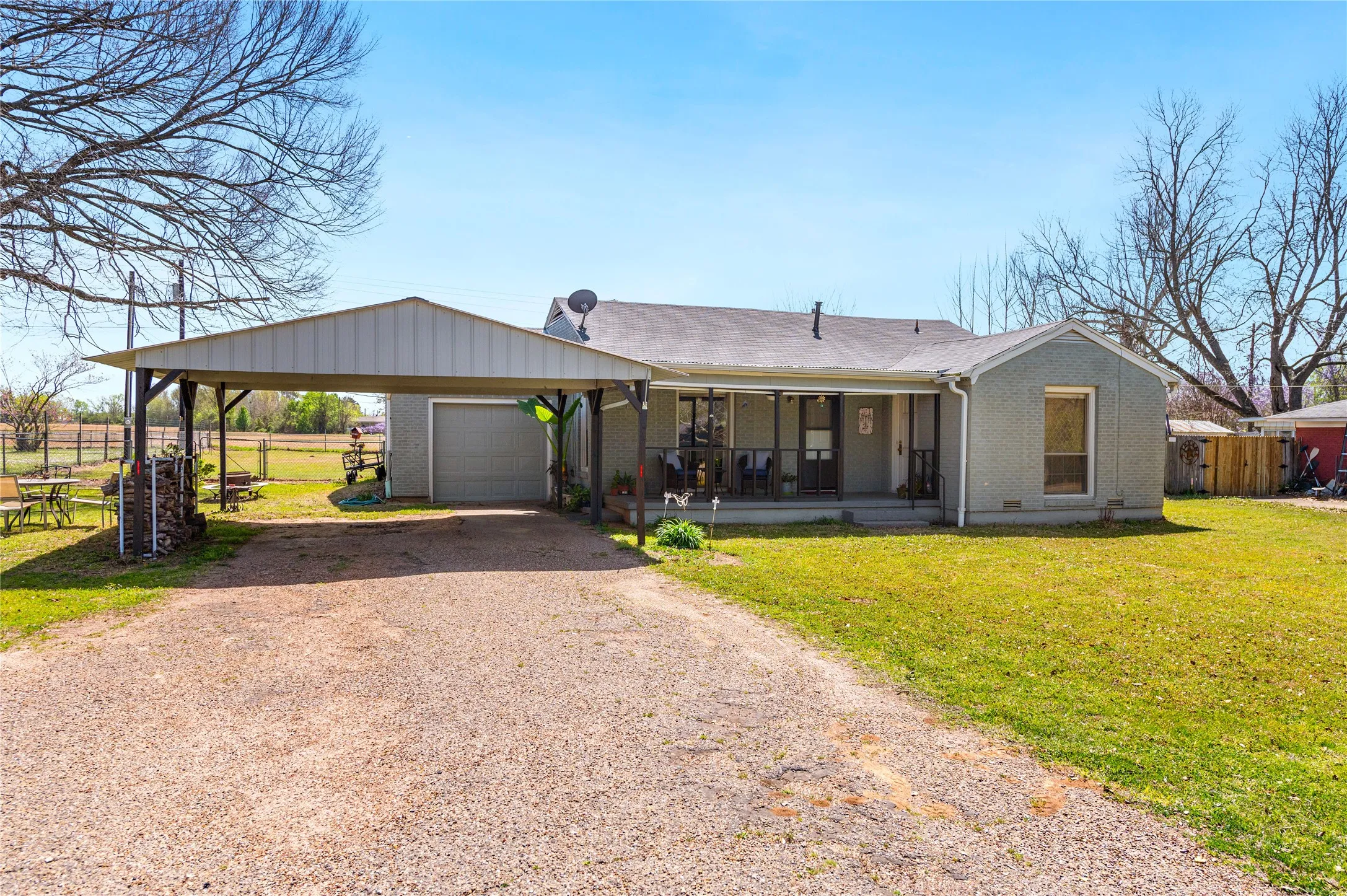 Ranch-style residence featuring a gravel driveway, an attached carport, and a prominent garage door