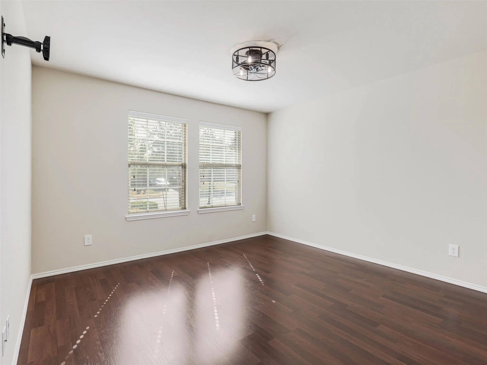 Dual windows with blinds, wood-finish flooring, and a ceiling-mounted light fixture
